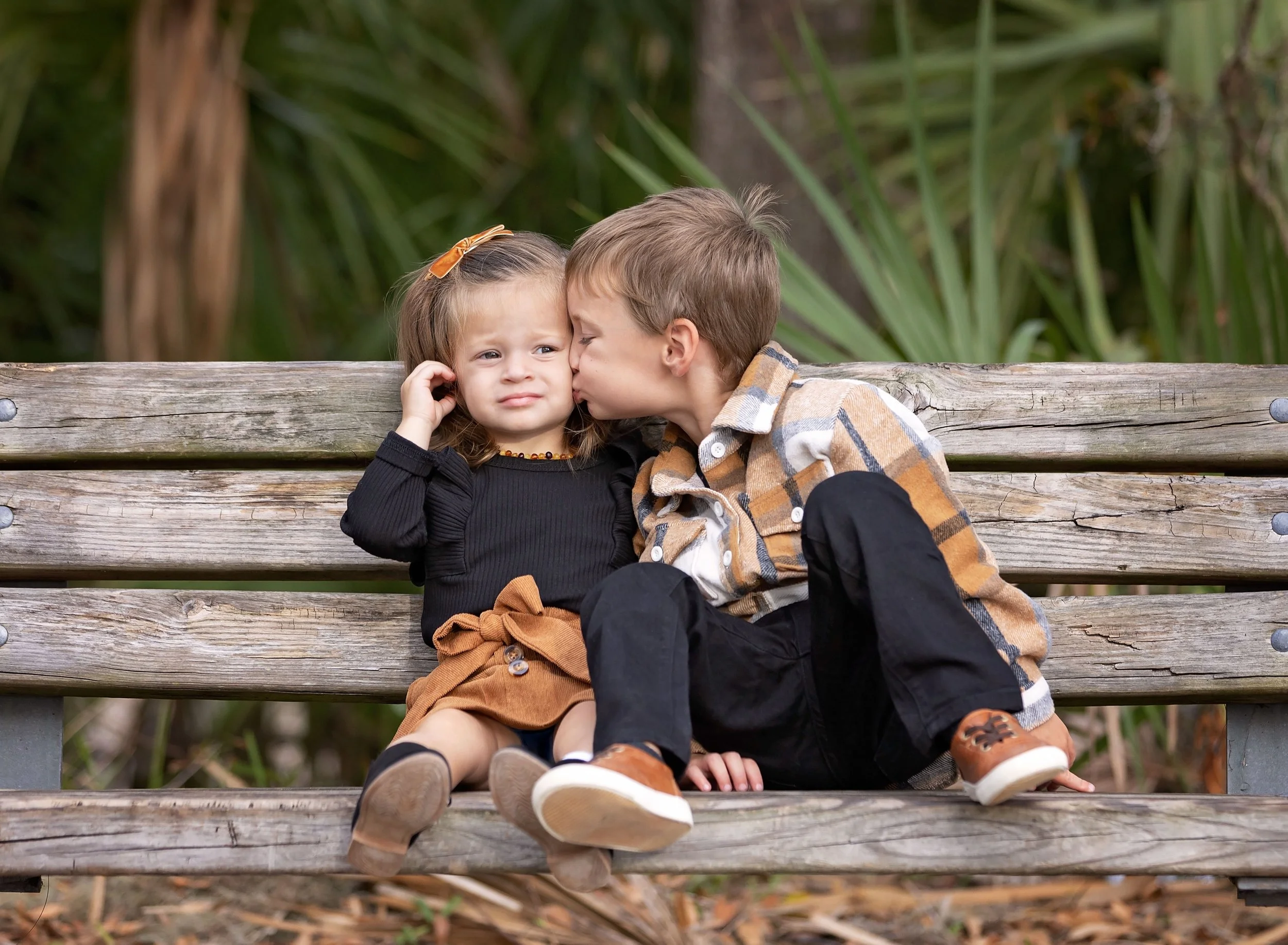 Big brother kissing little sister on park bench in Port Charlotte FL
