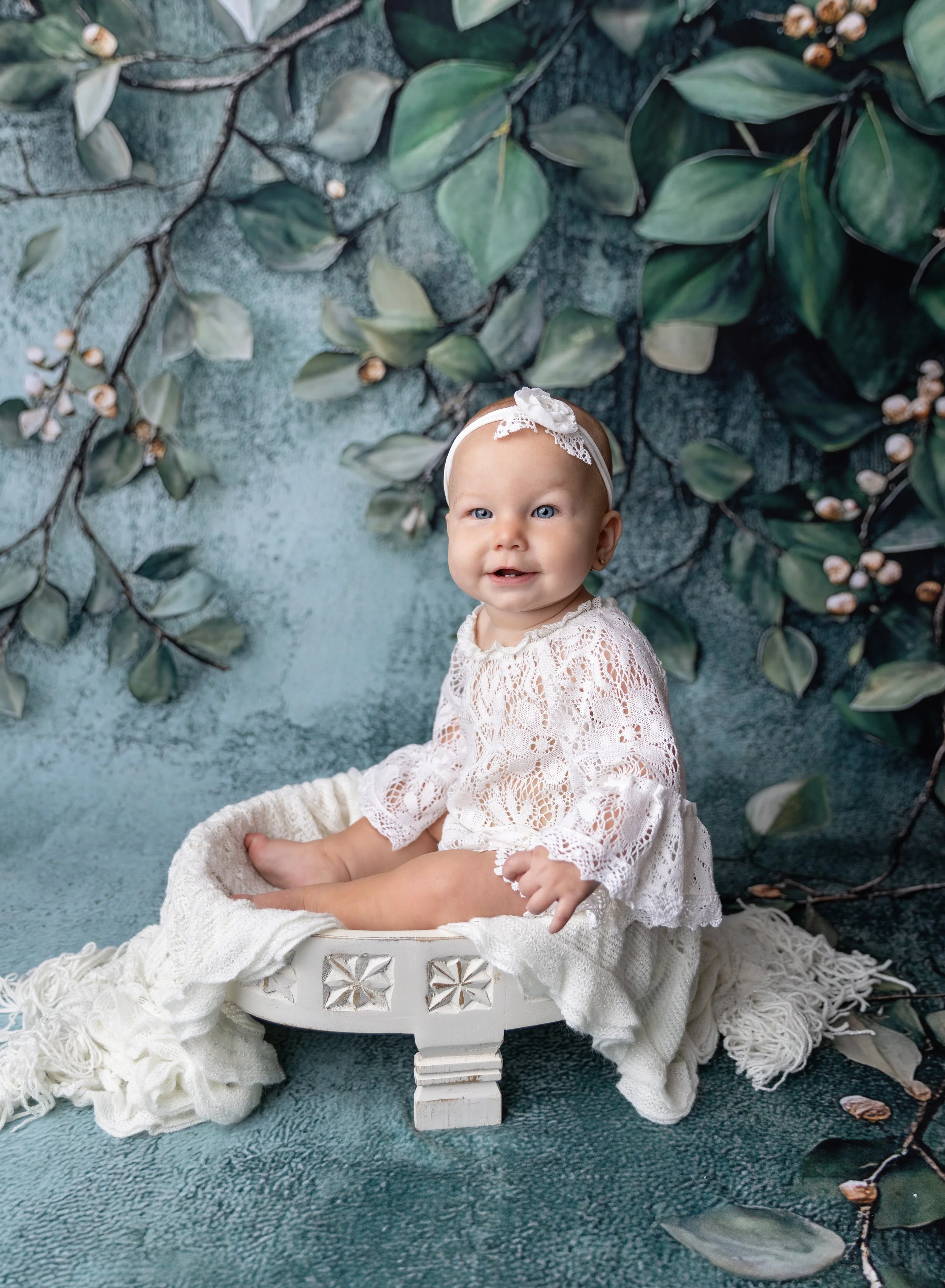 Six month old girl in vintage lace on green floral backdrop in North Port FL photo studio