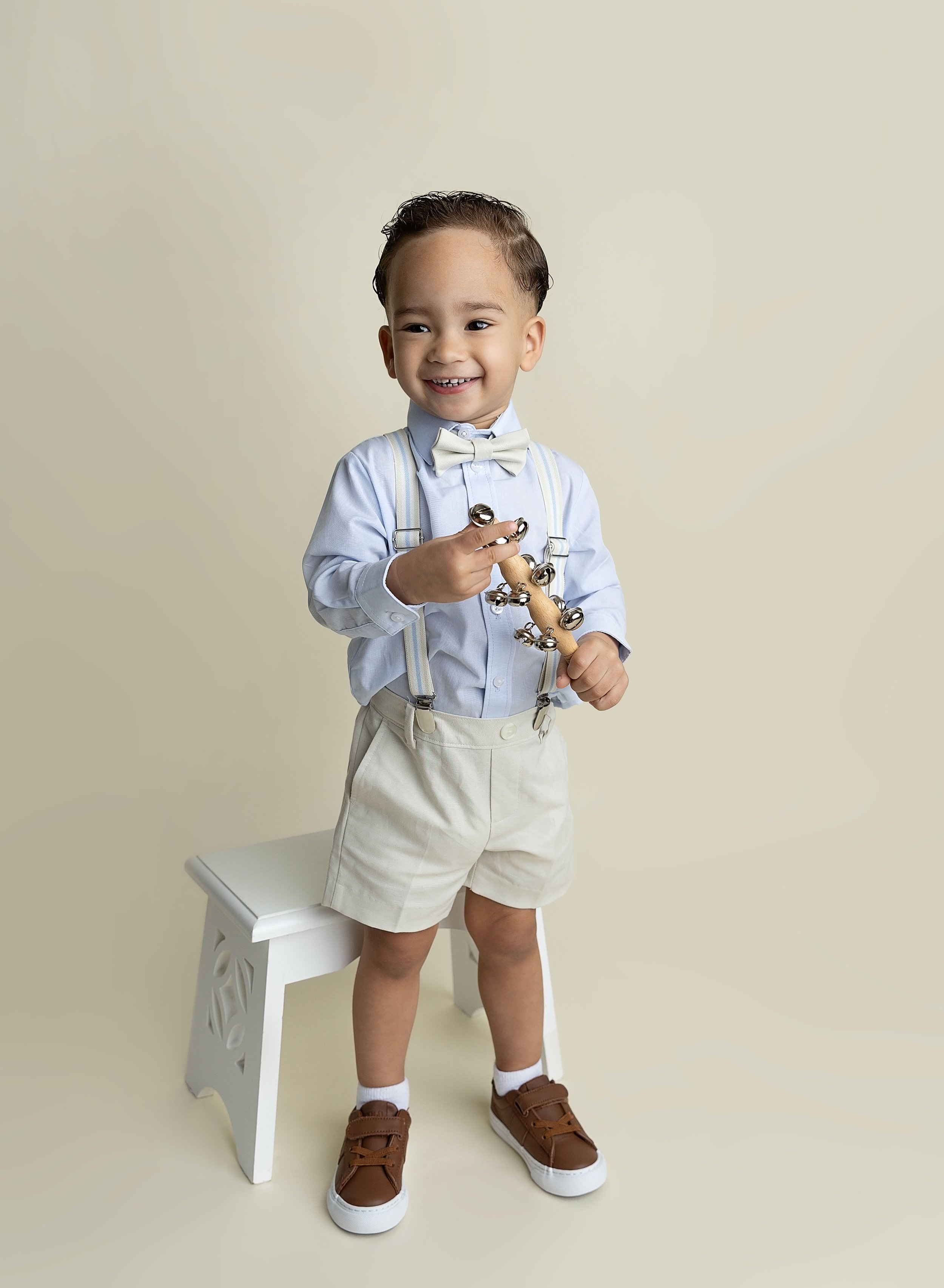 Two year old boy in shorts on cream. backdrop in North Port FL photo studio