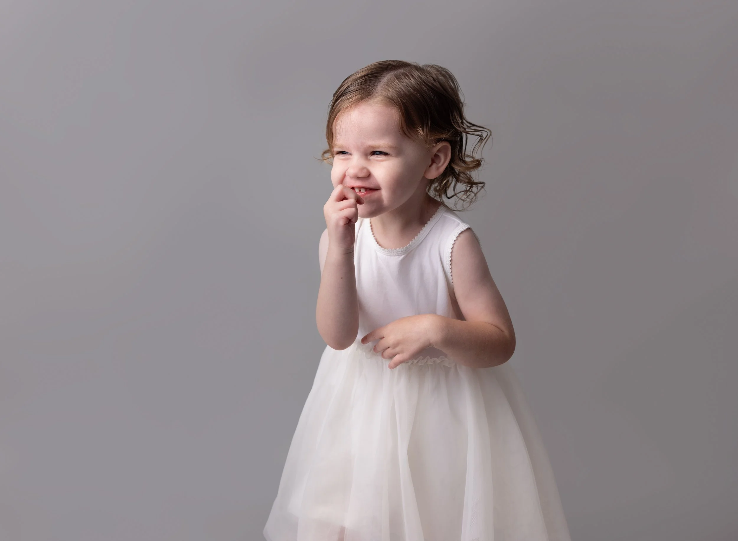 Three year old girl on grey backdrop in white dress in Port Charlotte, FL photo studio