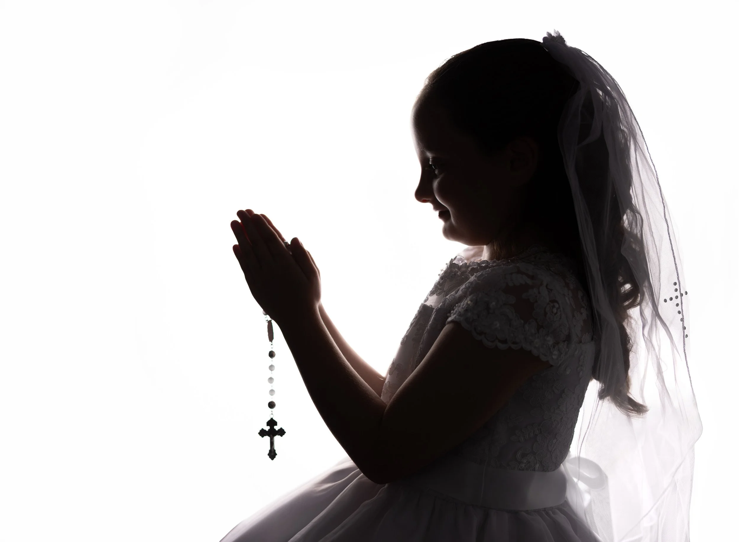 Silhouette of young girl holding the rosary for first communion Port Charlotte FL