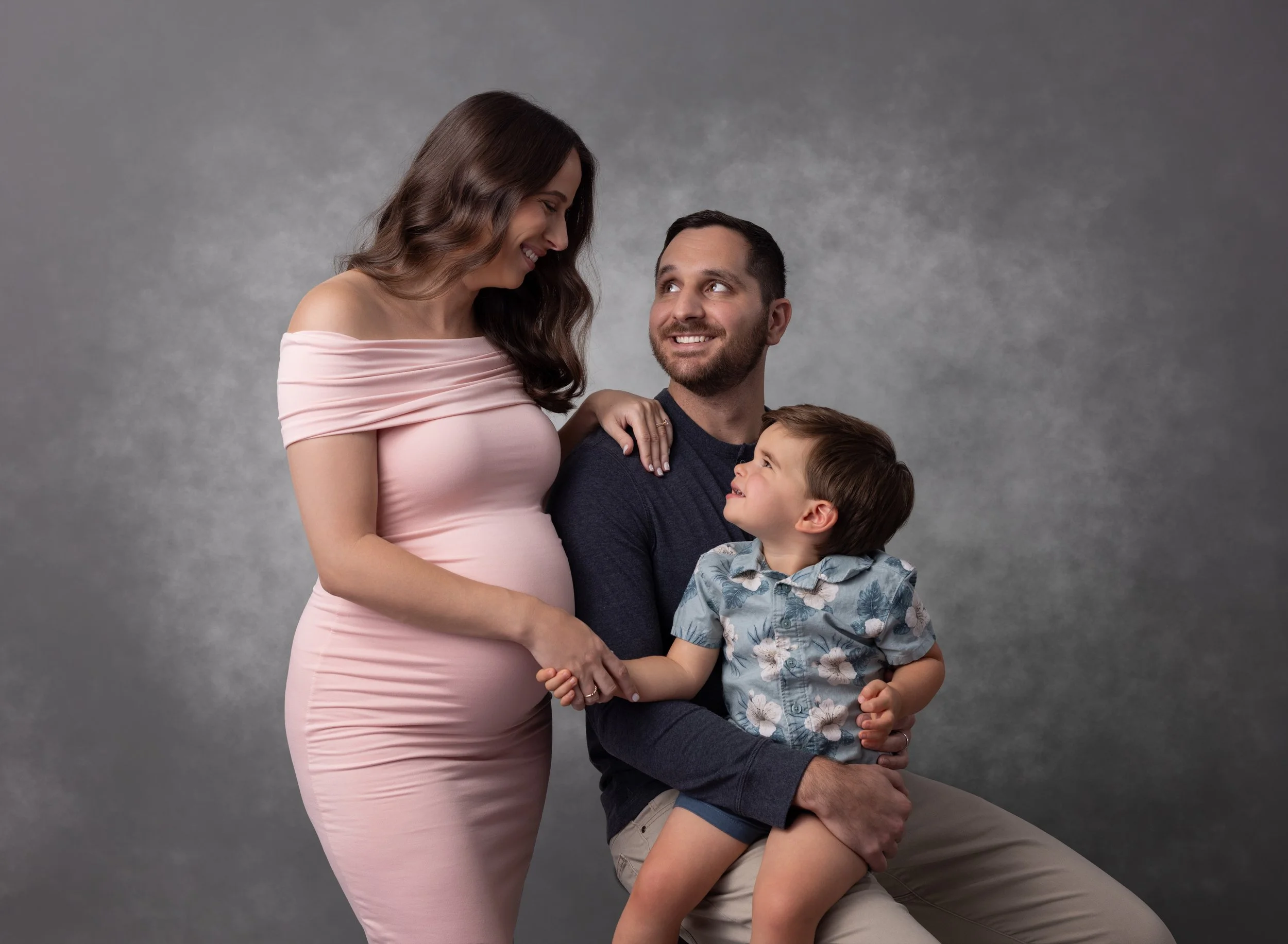 Pregnant mom with dad and toddler in pink gown in Cape Coral photo studio