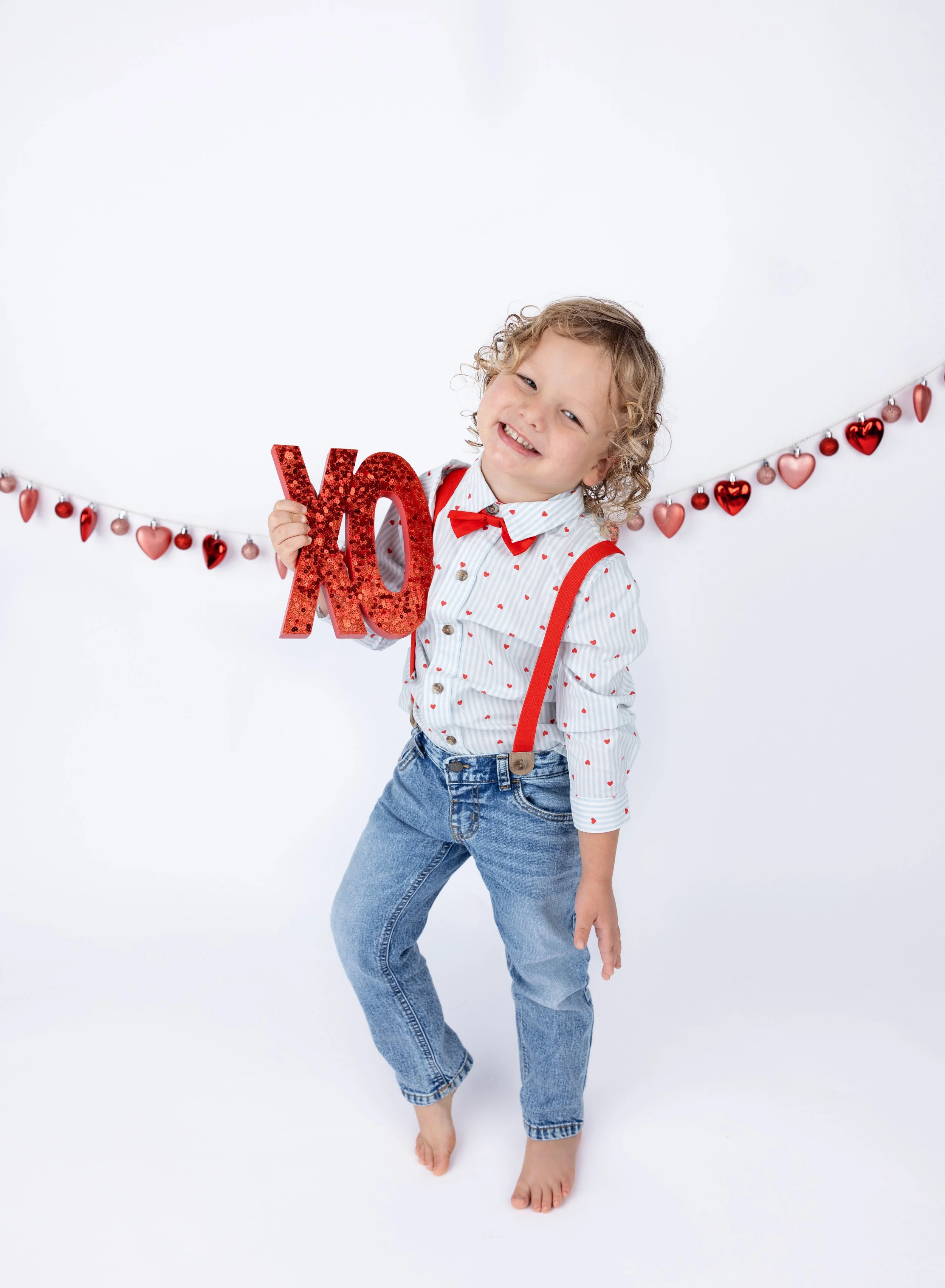 Four year old boy in jeans on Valentine backdrop in photo studio