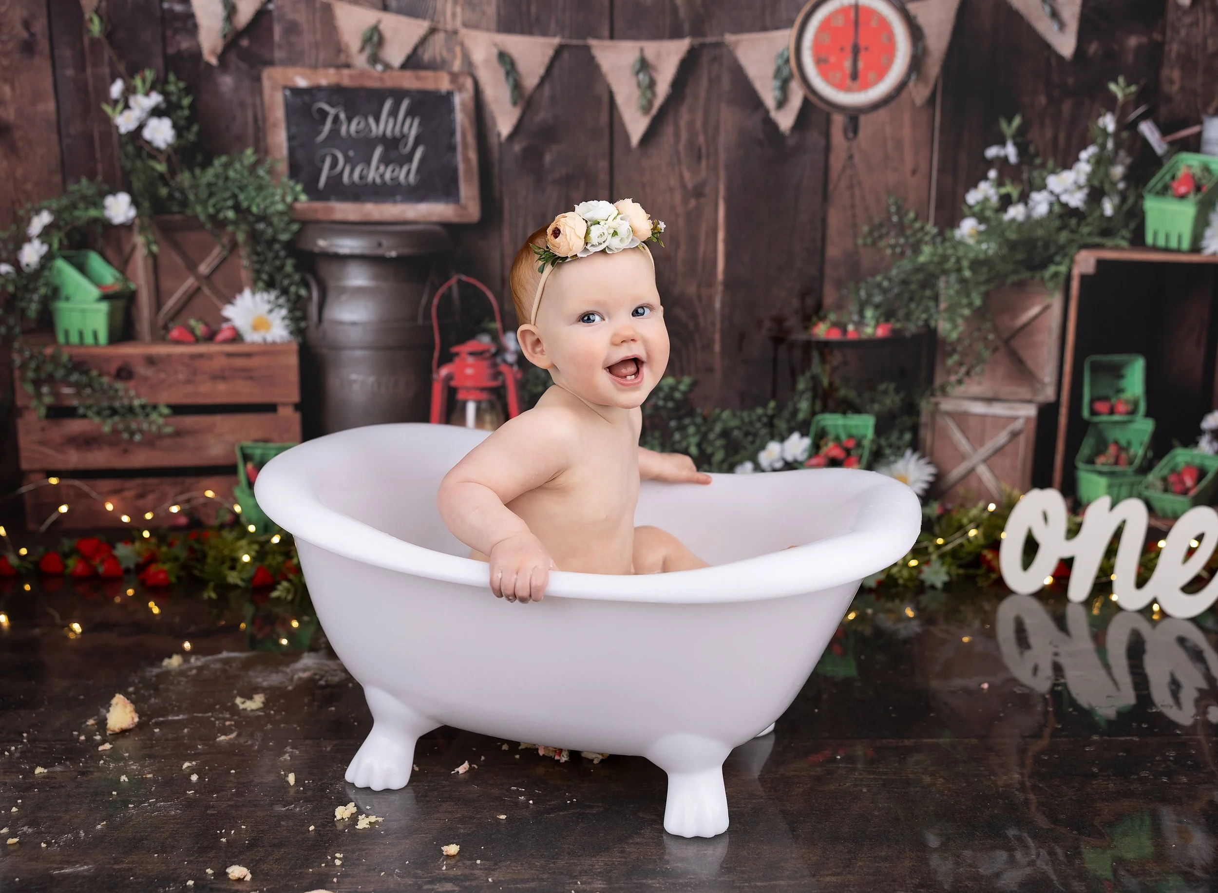 First birthday cake smash bath on strawberry backdrop in Port Charlotte FL photo studio.