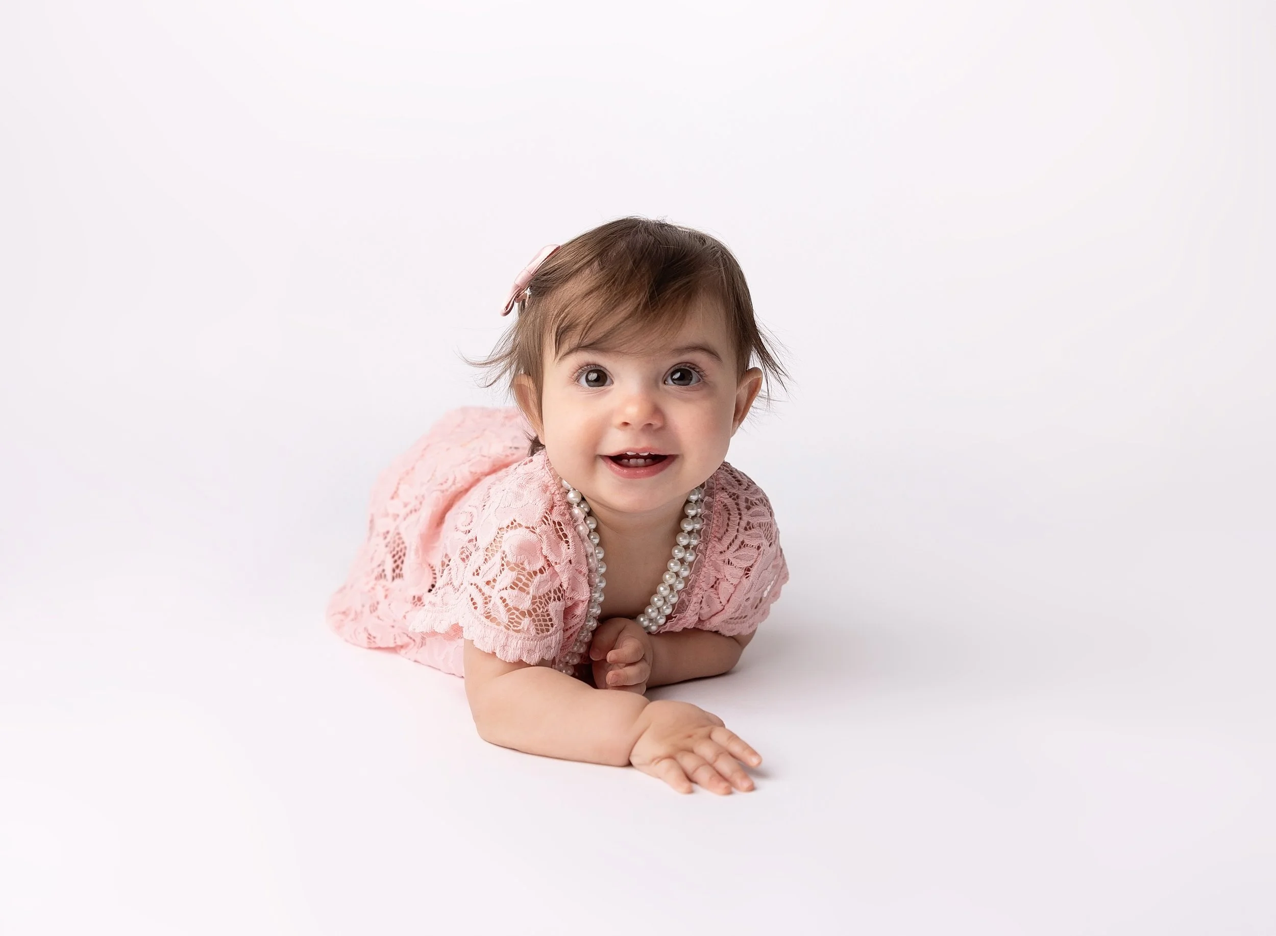 One year baby girl on white backdrop and pink dress in photo studio Port Charlotte, FL