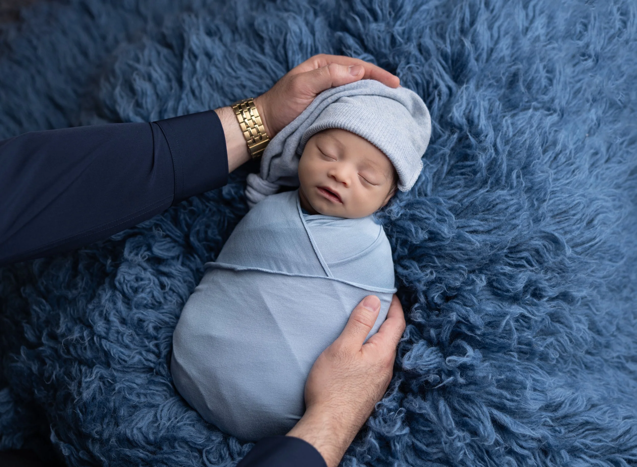 Newborn boy swaddled in dad's hands in Venice FL studio