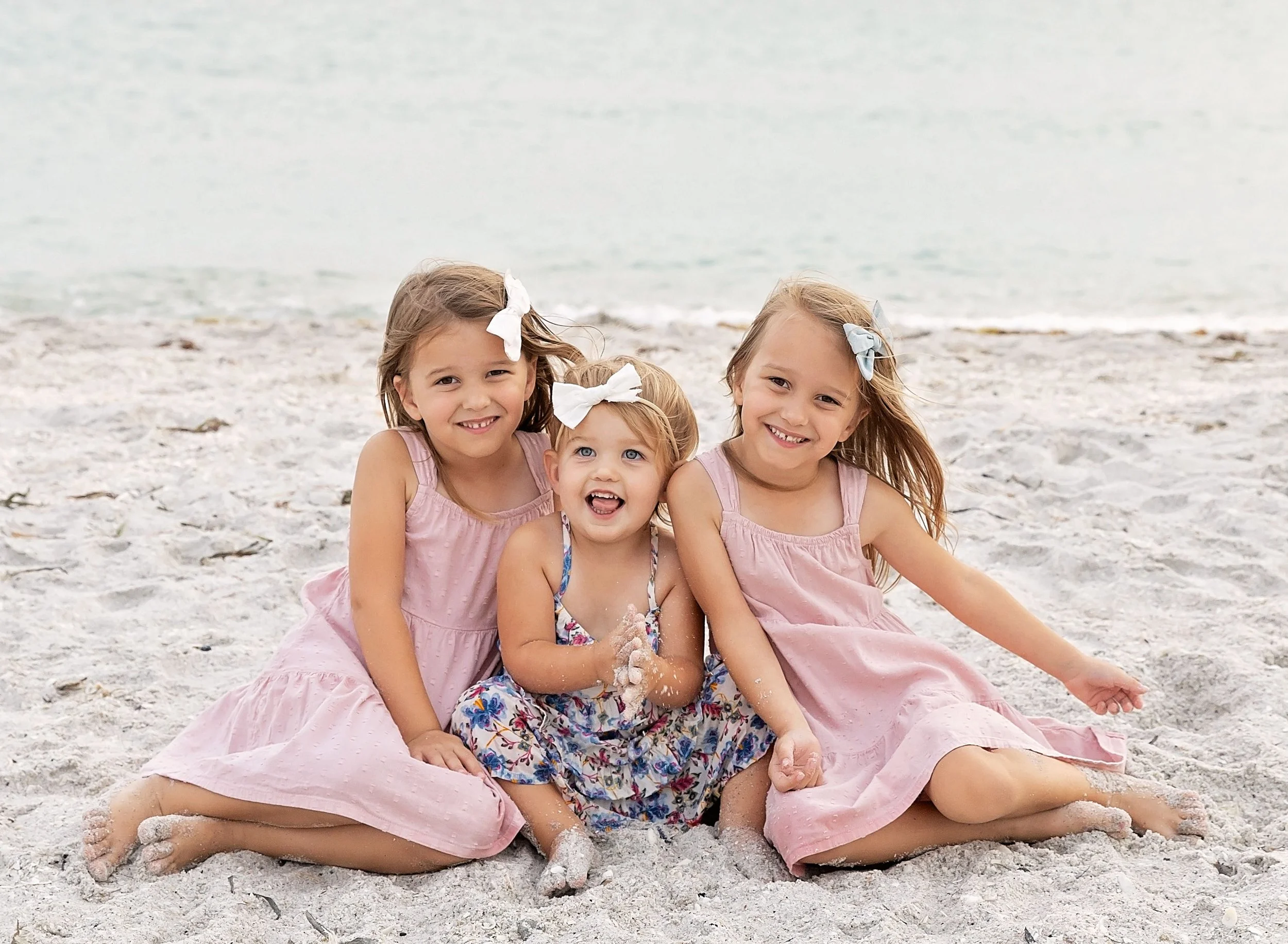 Three sisters in pink dresses on beach in Venice Fl