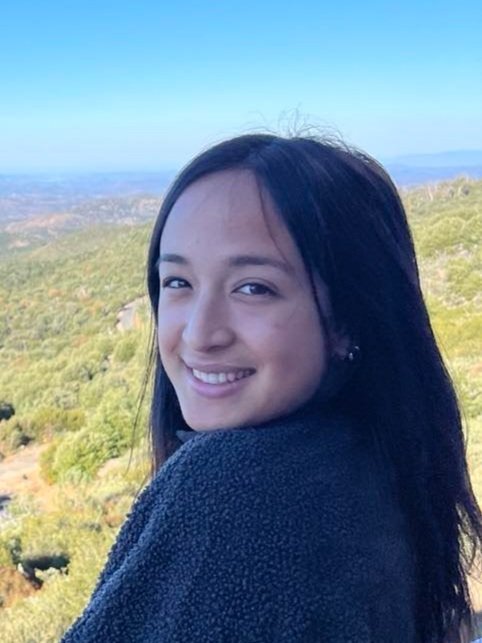 Smiling person outdoors with green landscape background