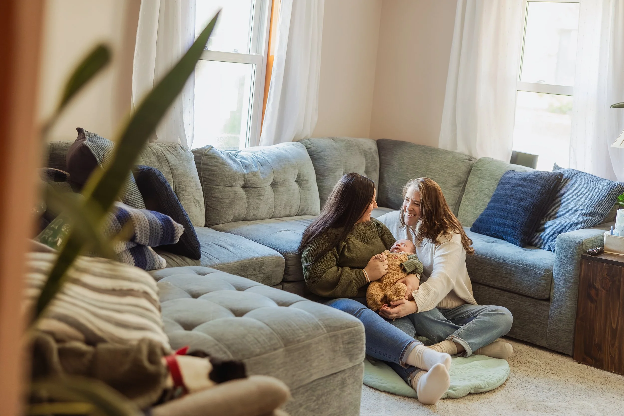 Parent holding newborn near window light during winter in-home newborn photography session in Southern NH