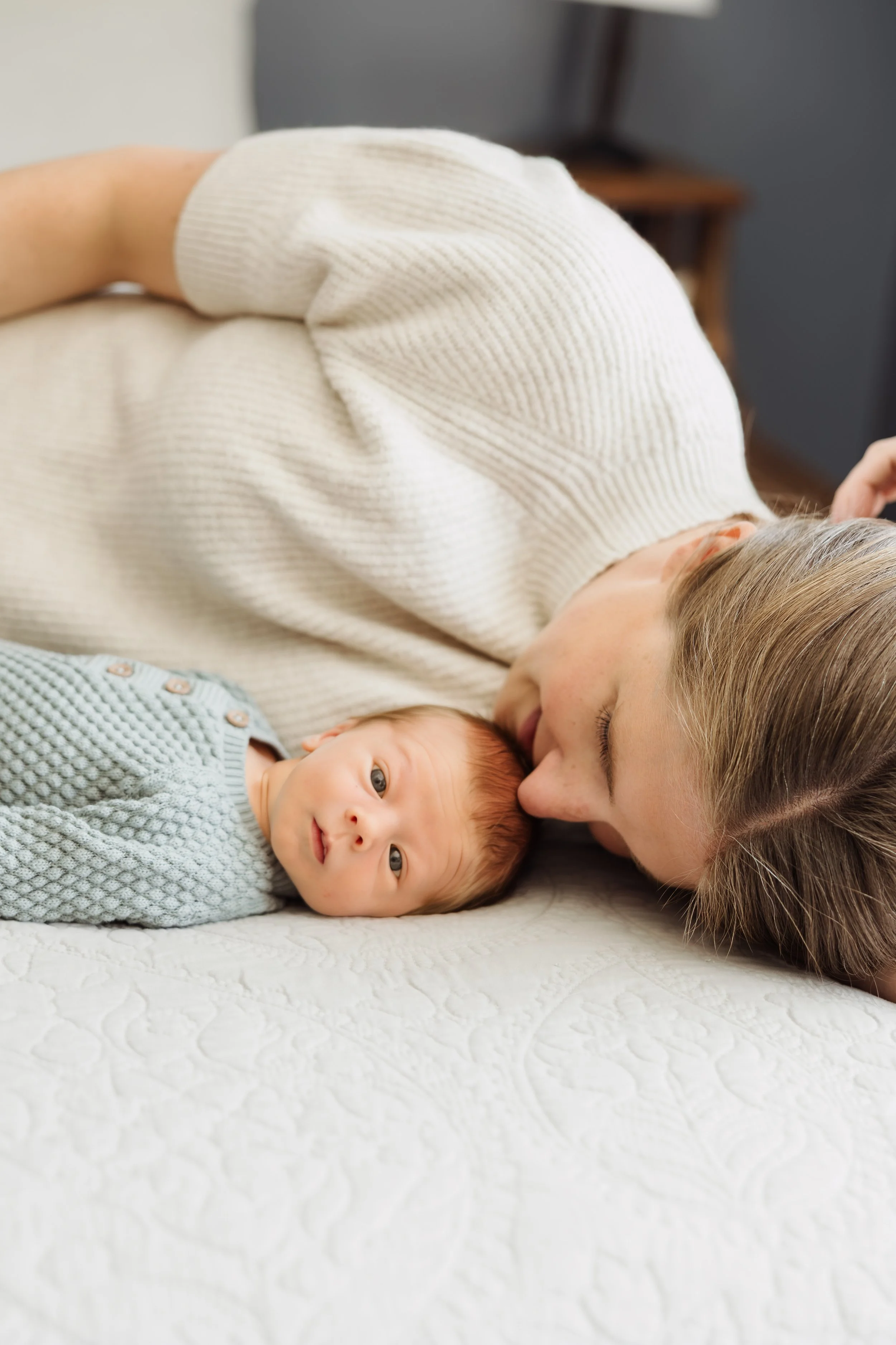 In-home lifestyle newborn photography in Southern New Hampshire capturing a quiet snuggle moment between parent and baby.