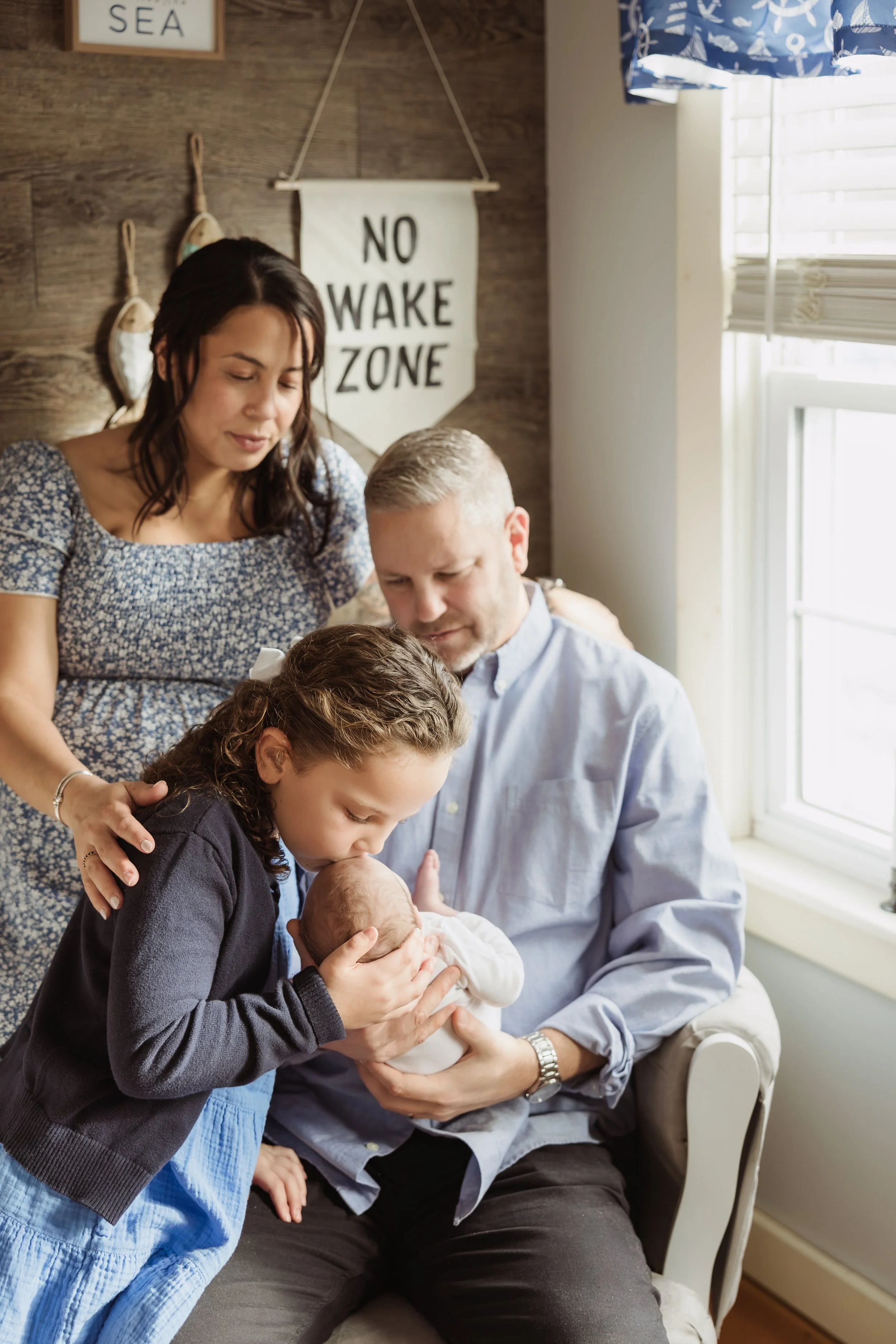 Simple lifestyle newborn photo capturing a sister kissing her baby brother's head during an in-home session in Southern New Hampshire.