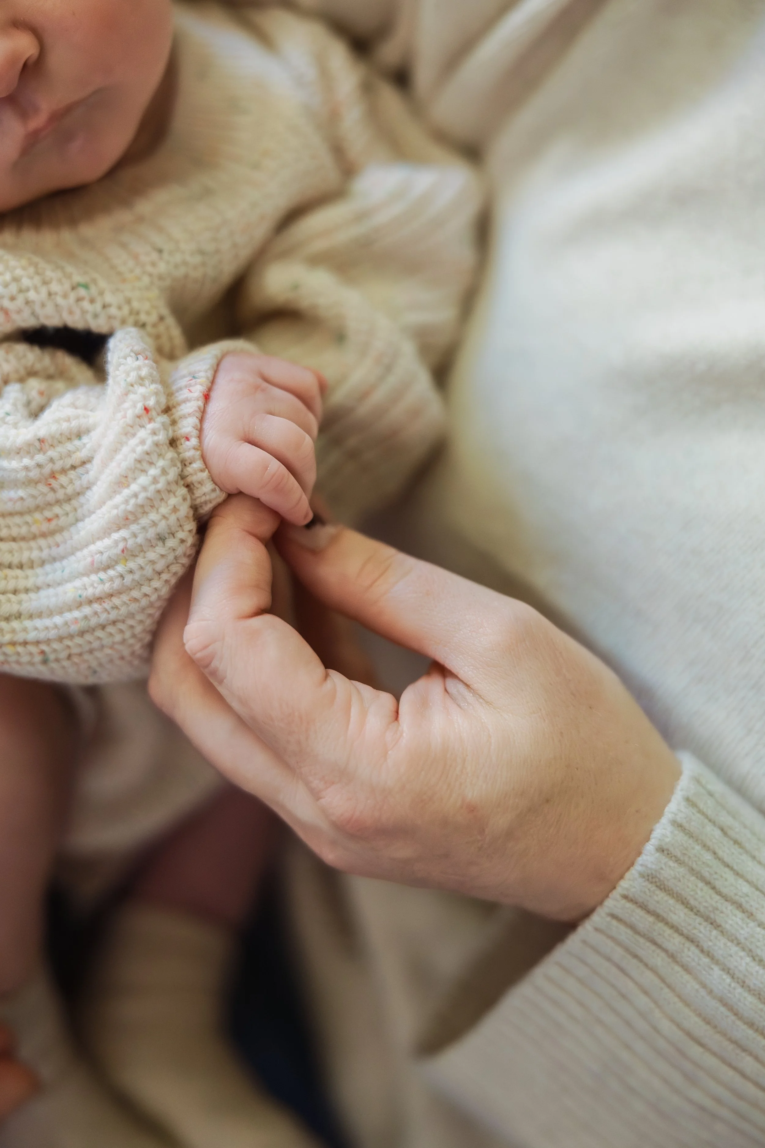 Newborn baby hand resting in parent's palm during in-home lifestyle newborn session in Southern NH.