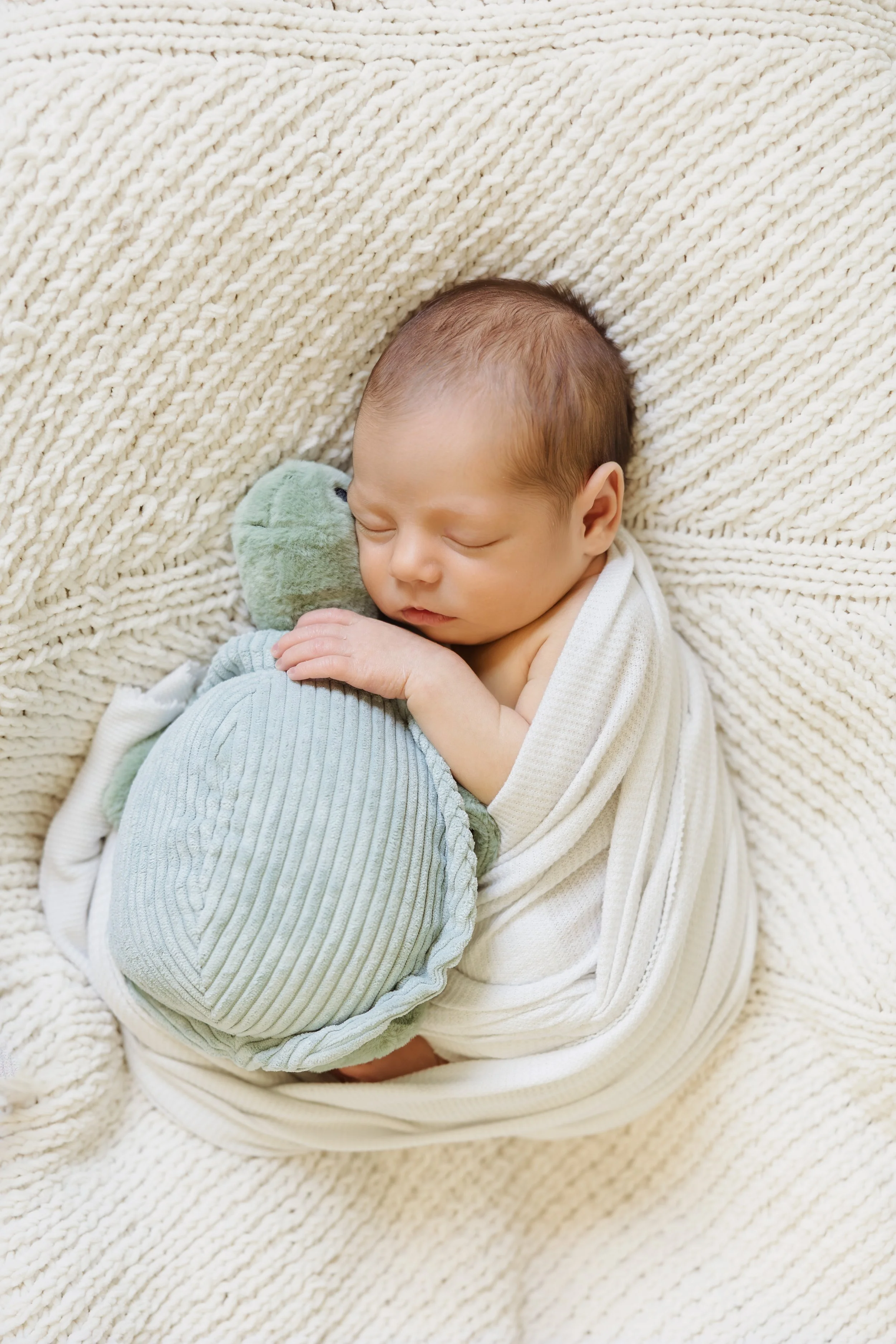 A baby snuggling a stuffed animal during  newborn photography session in Southern New Hampshire.