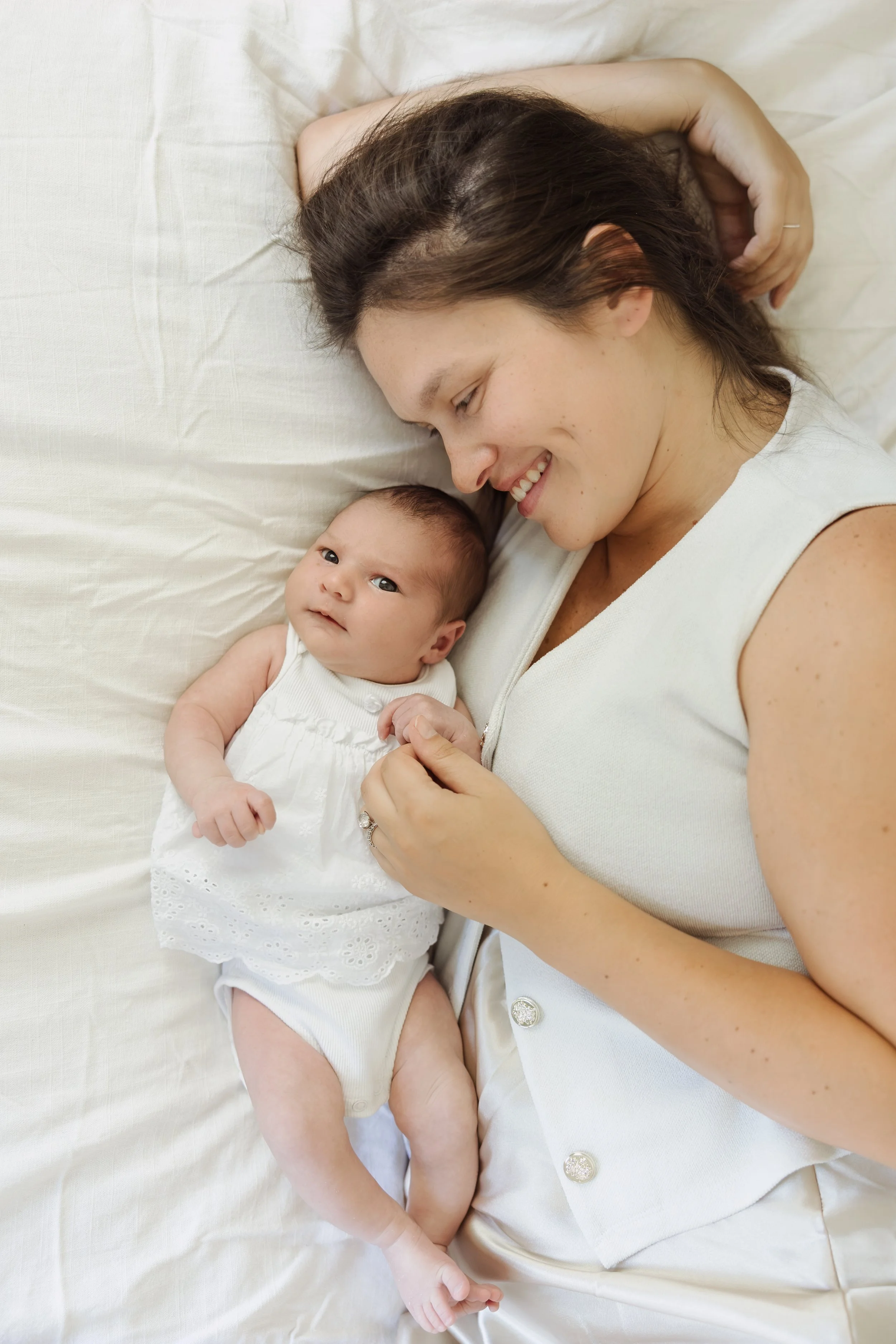 In-home newborn photographer Northern Massachusetts captures parent holding older newborn during lifestyle session