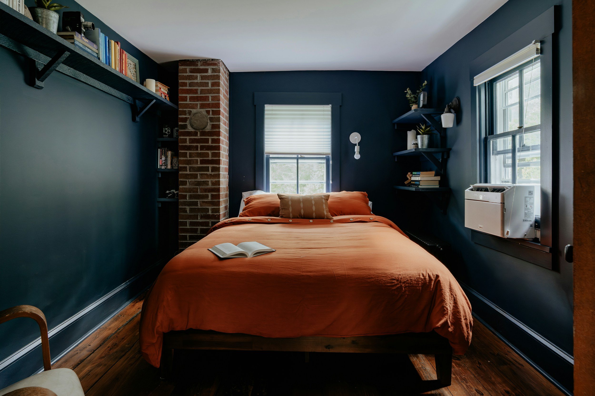 Dark painted room with bed featuring an orange bedspread