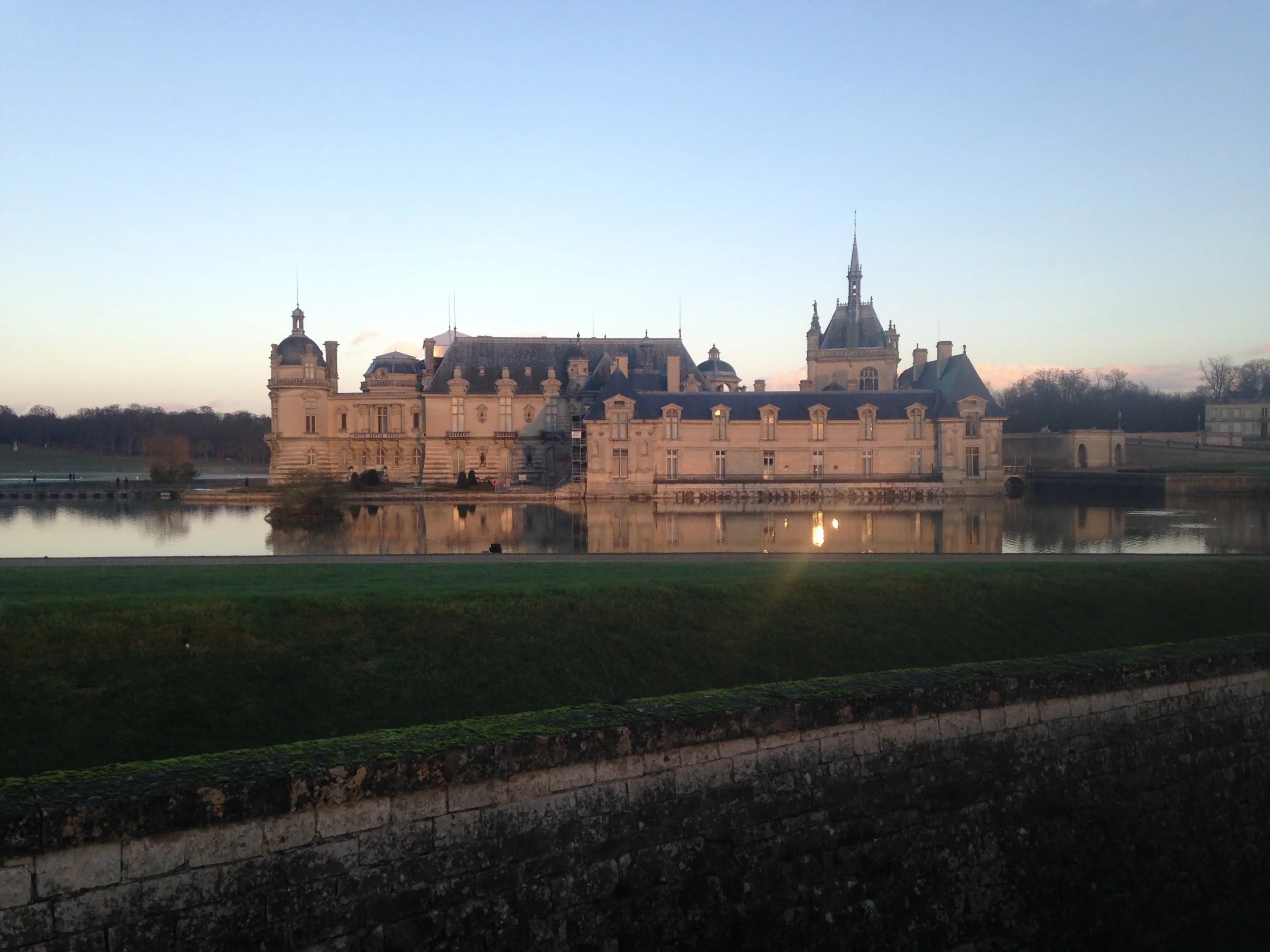 Château de Chantilly reflected in still water at golden dawn — setting for restorative workshops and retreats