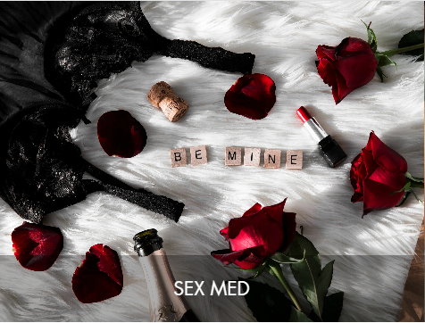 A romantic setup with red roses, scattered rose petals, a bottle of champagne, a lipstick, and the words 'BE MINE' spelled out with letter tiles on a white furry surface, with the text 'SEX MED' overlaid at the bottom.