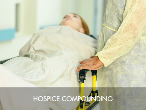 A patient lying in a hospital bed covered with a blanket, with a healthcare worker in protective gown pushing the bed.