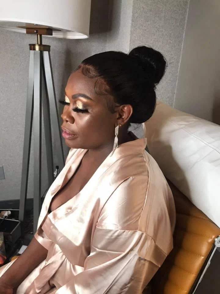 Woman in a silk robe with makeup sitting near a lamp.