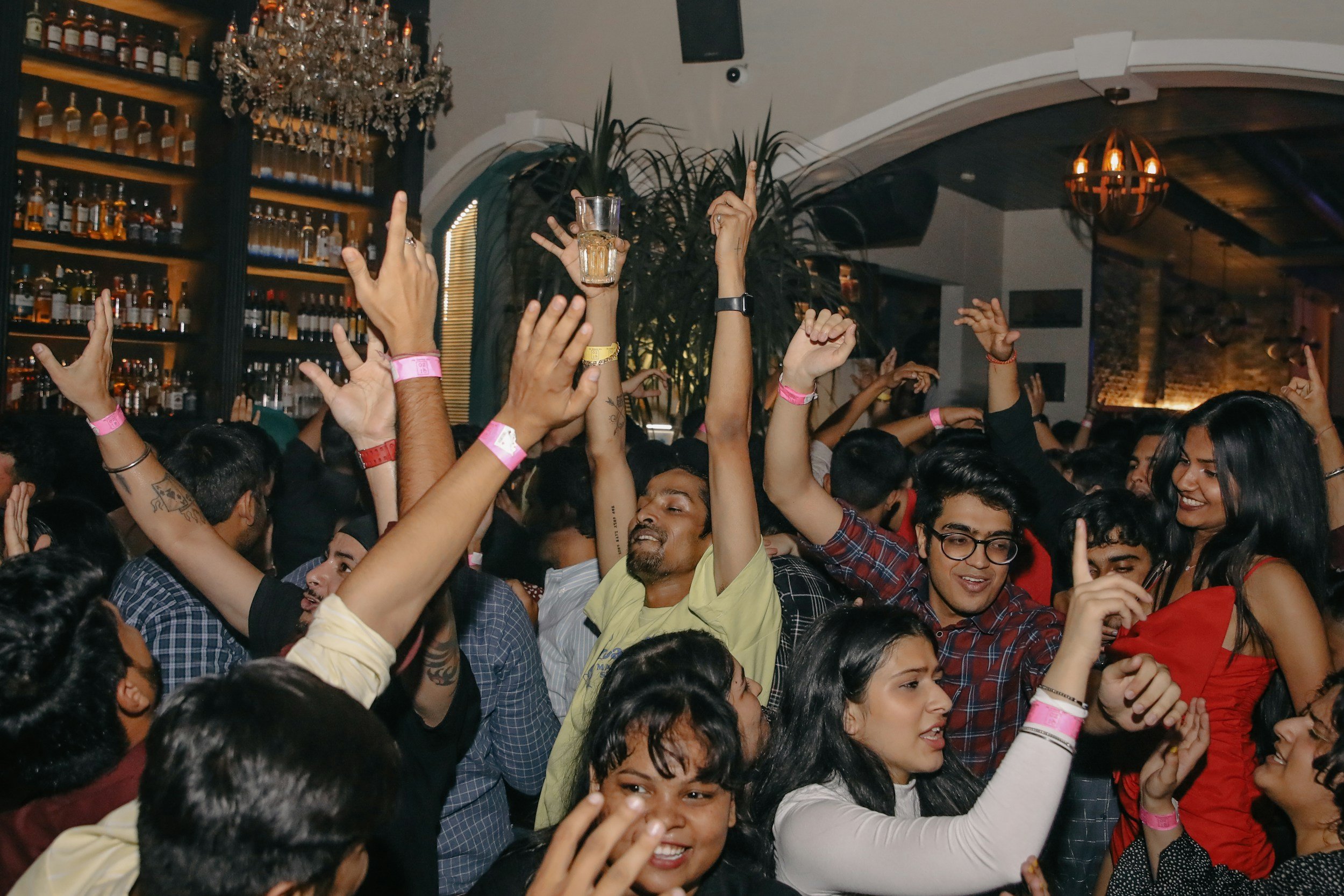 people dancing and throwing their hands in the air at a bar