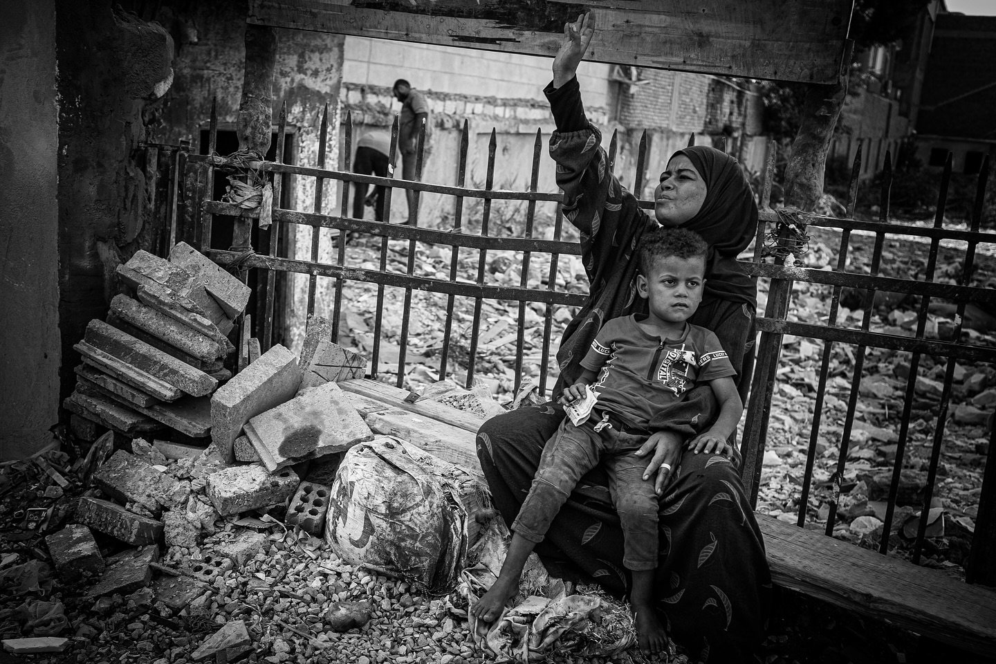 In the streets of Cairo, resilience shines through the rubble. A mother, her hand raised in a silent plea, holds her child close, the weight of uncertainty etched into every corner. Life persists amid the ruins. #Cairo #StreetPhotography #resilience 