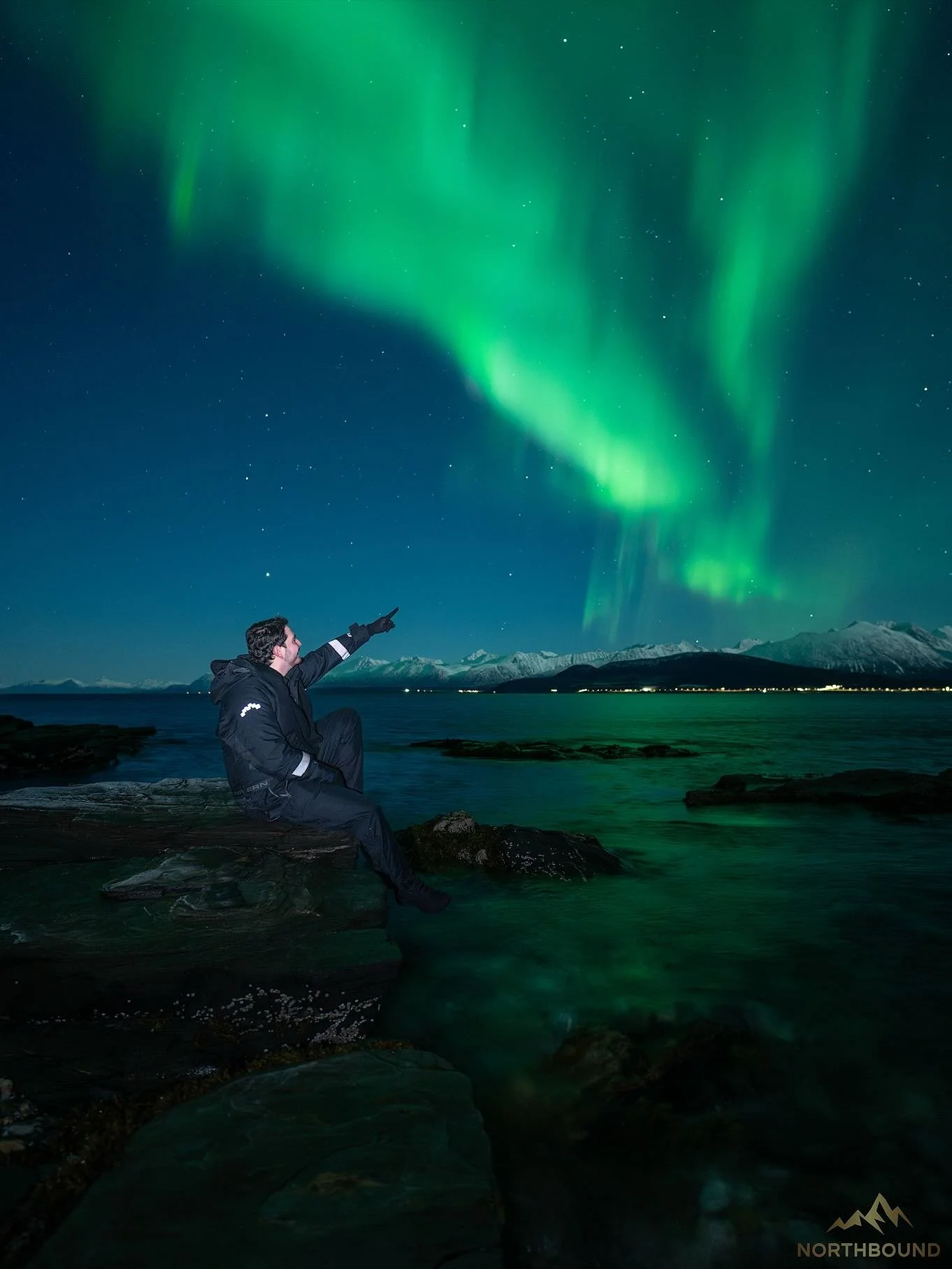 1st November 💚. We welcomed November with another beautiful night in a location that is straight off a postcard. A rocky shoreline next to the fjord with the stunning Lyngen Alps illuminated by moonlight across the fjord while under a dancing arctic