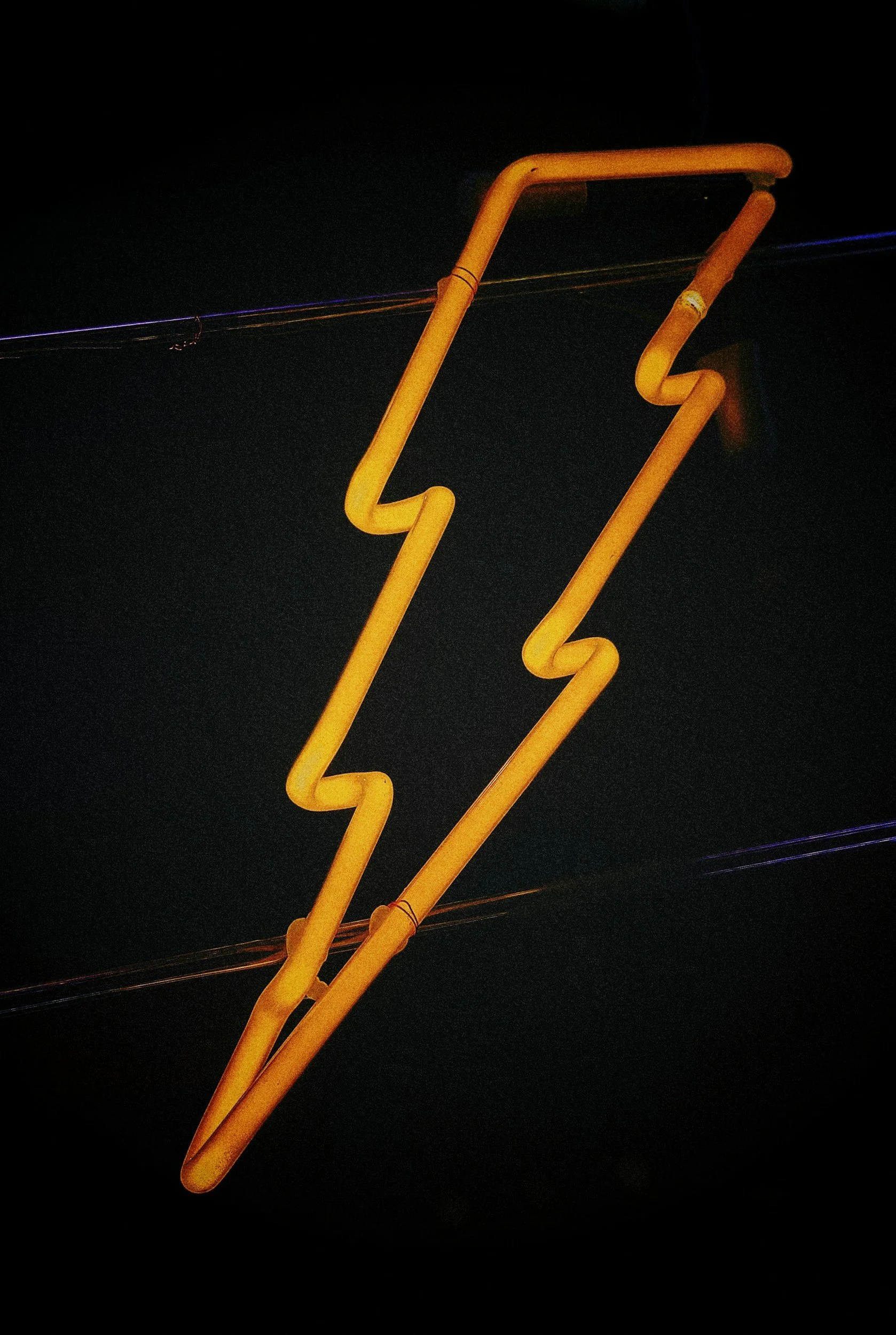 A neon sign shaped like a yellow lightning bolt against a dark background.