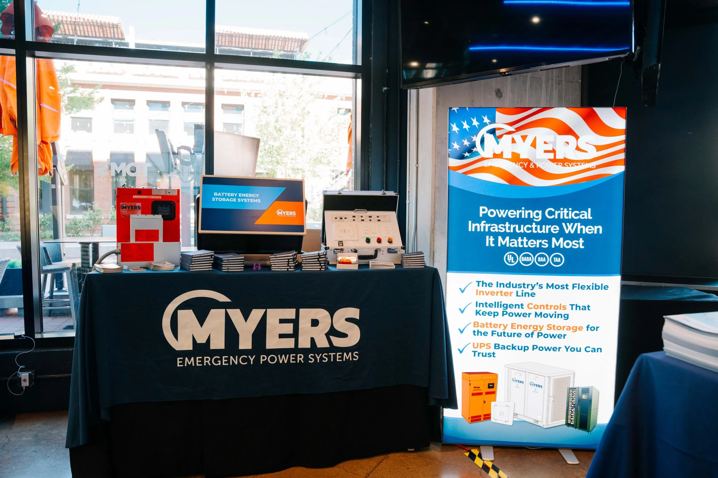Trade show booth for Myers Emergency Power Systems featuring banners, displays, and equipment related to battery energy storage systems and power backup solutions.