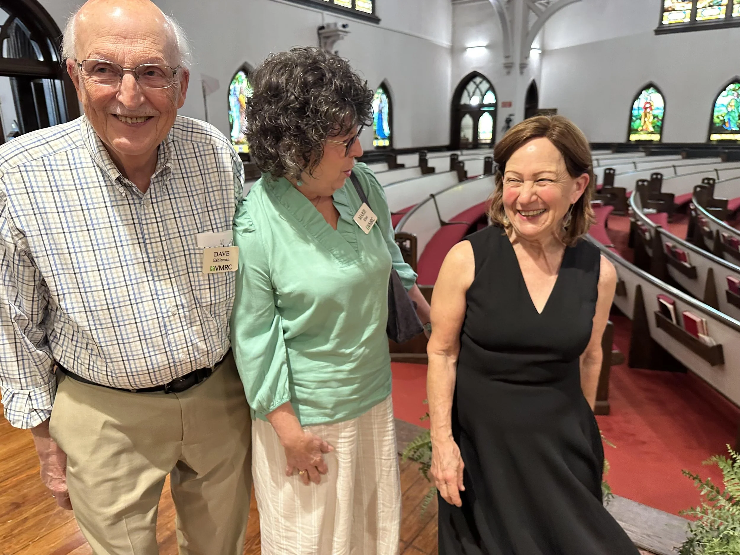 an elderly couple smiling and speaking with a musical performer