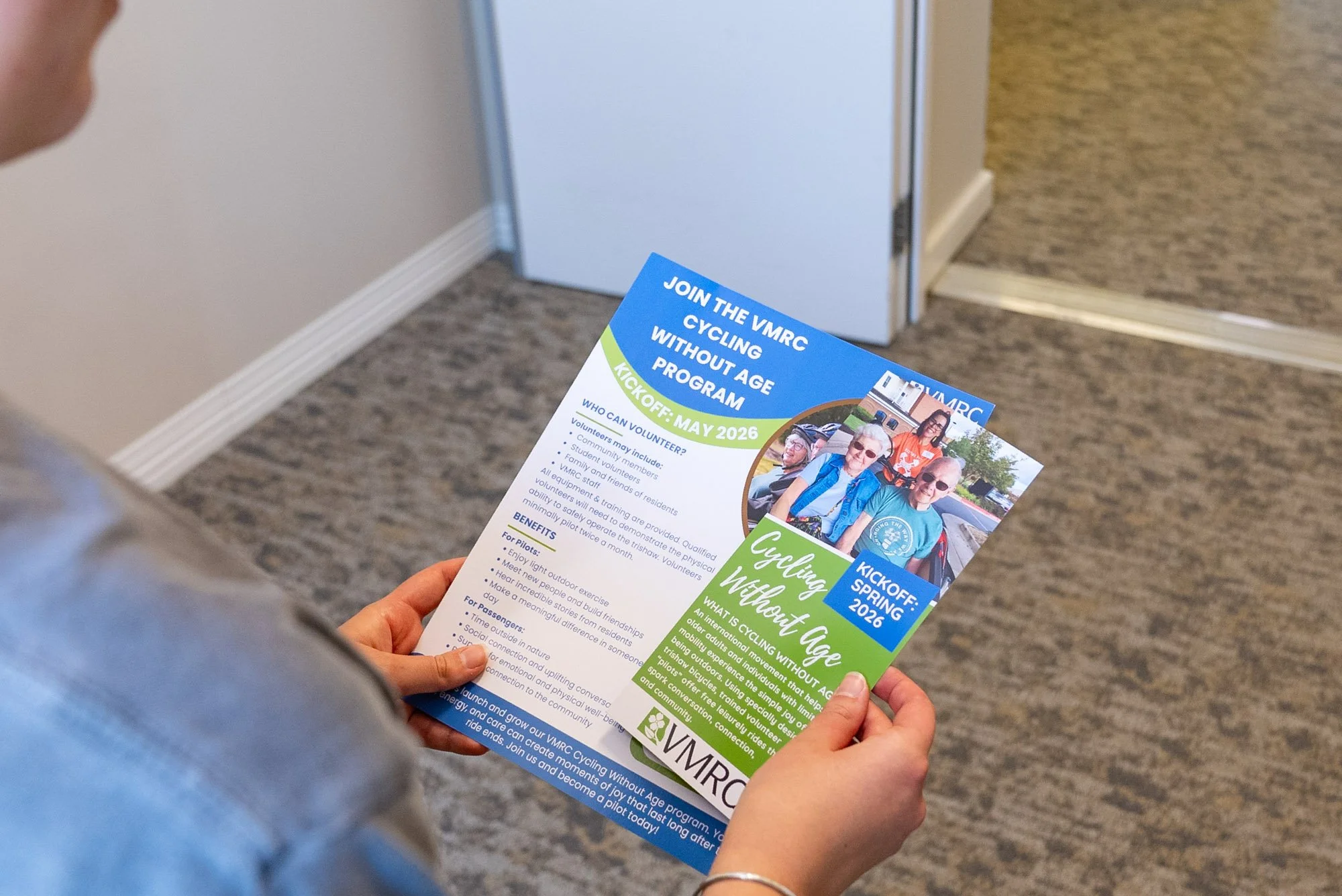 someone holding two informational documents about the cycling without age program
