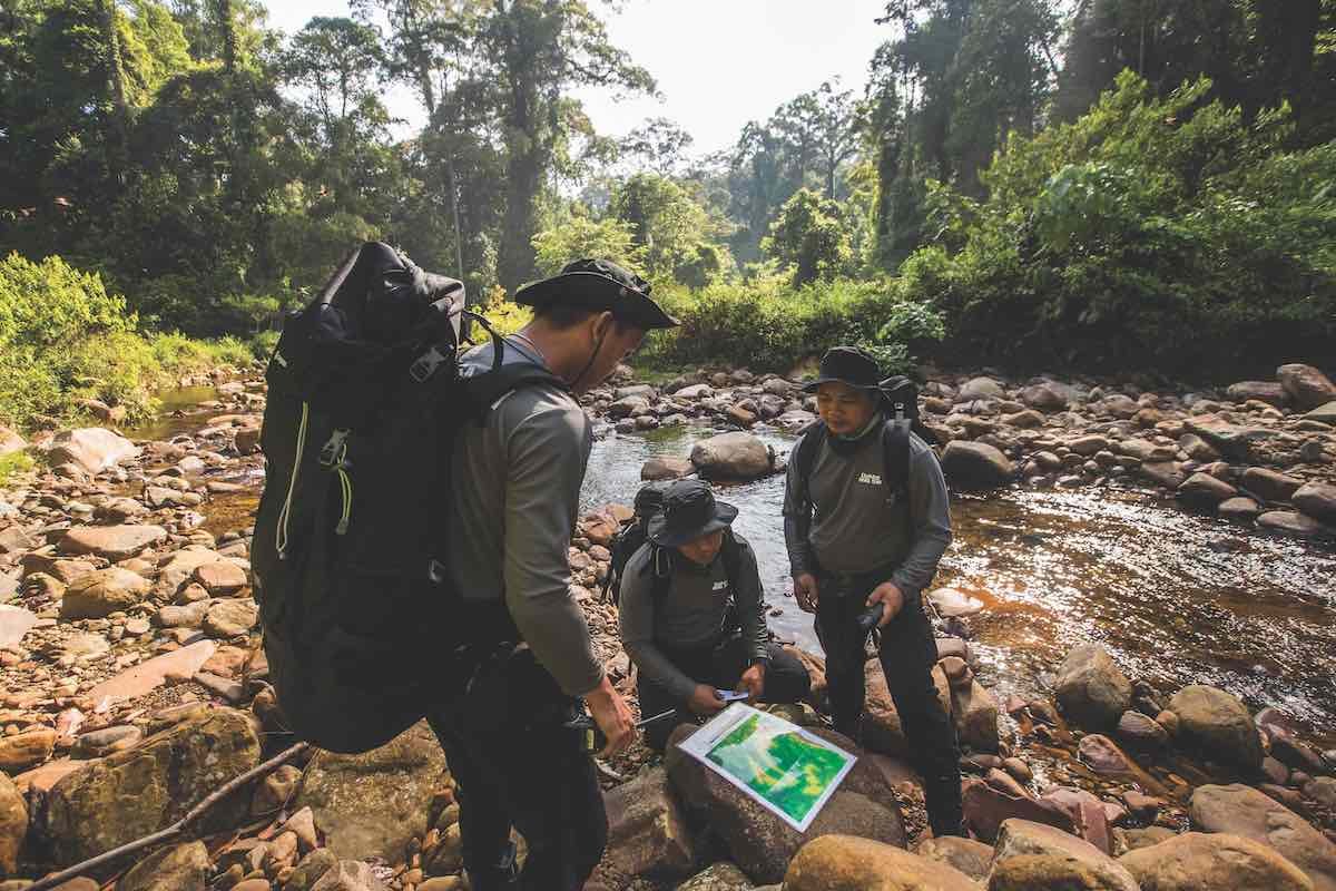 DaMaI Park Protection Team navigates rugged jungle terrain on foot.
