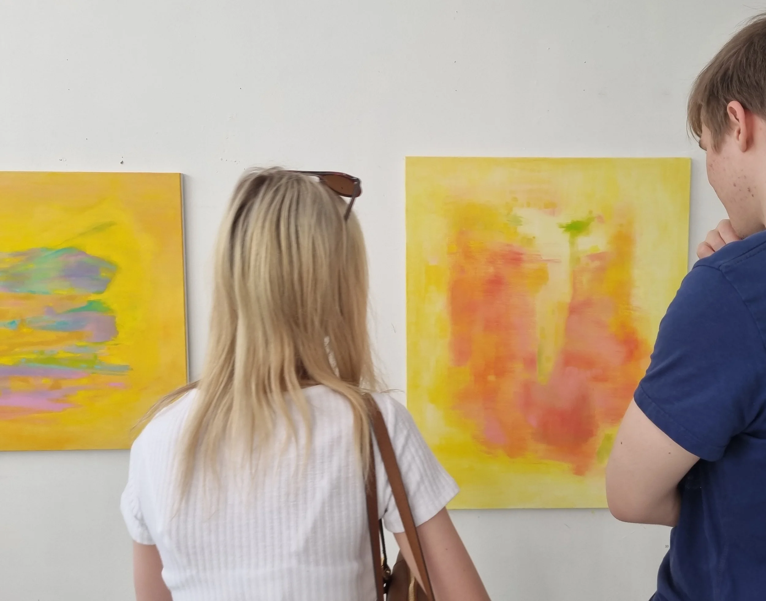 Installation view,  Helsinki, 2024. Two people looking at Satu Metsola's abstract oil paintings