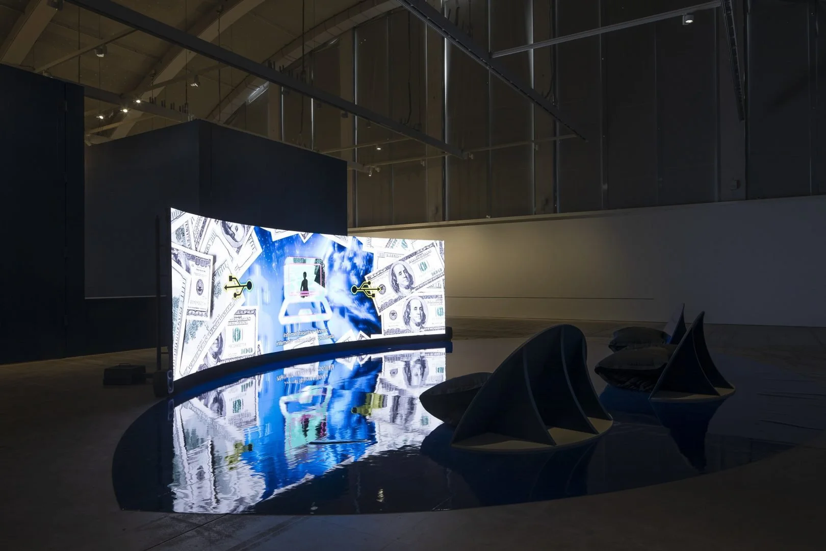 Large digital screen displaying a graphic of dollar bills and a smartphone, with locks on both sides, in a dark modern room with chairs reflected in a rounded table.