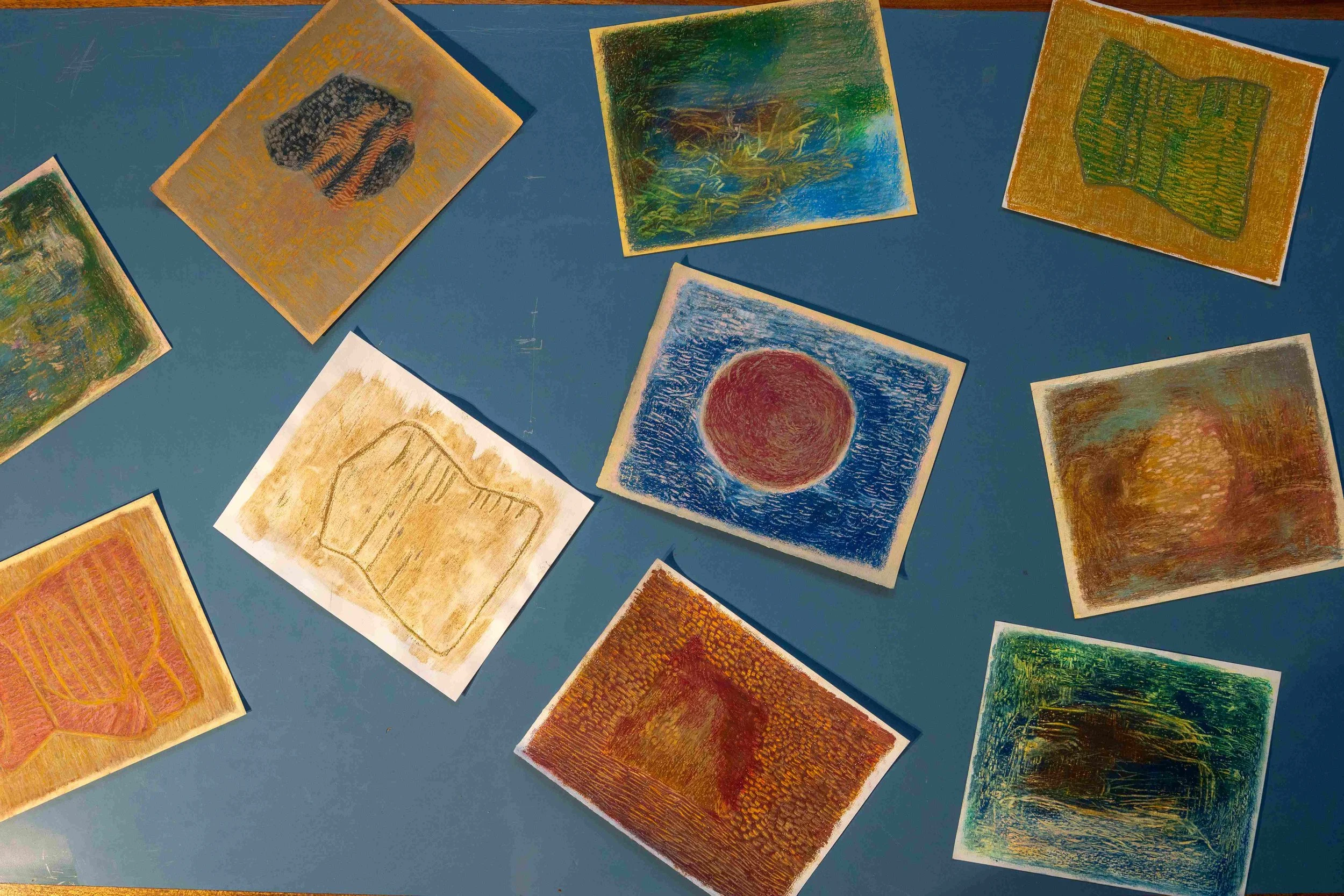 Finnish artist Satu Metsola's various oil pastel paintings displayed on the table