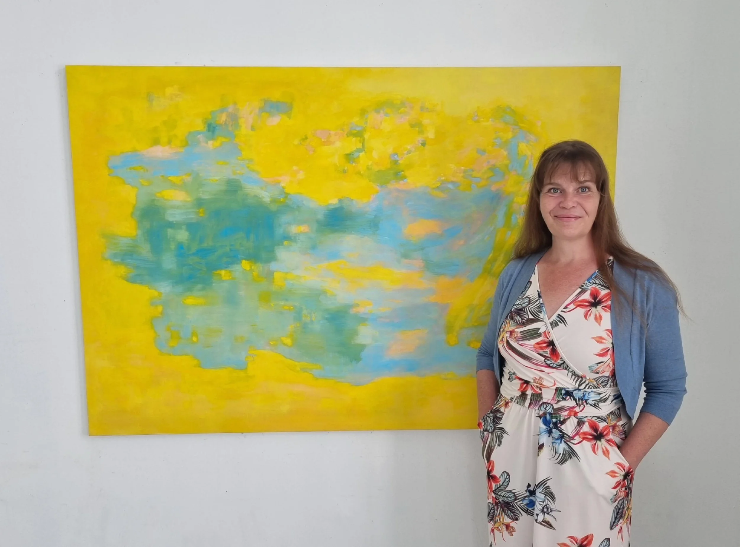 Finnish contemporary artist Satu Metsola posing in front of her large artwork, yellow oil painting on canvas