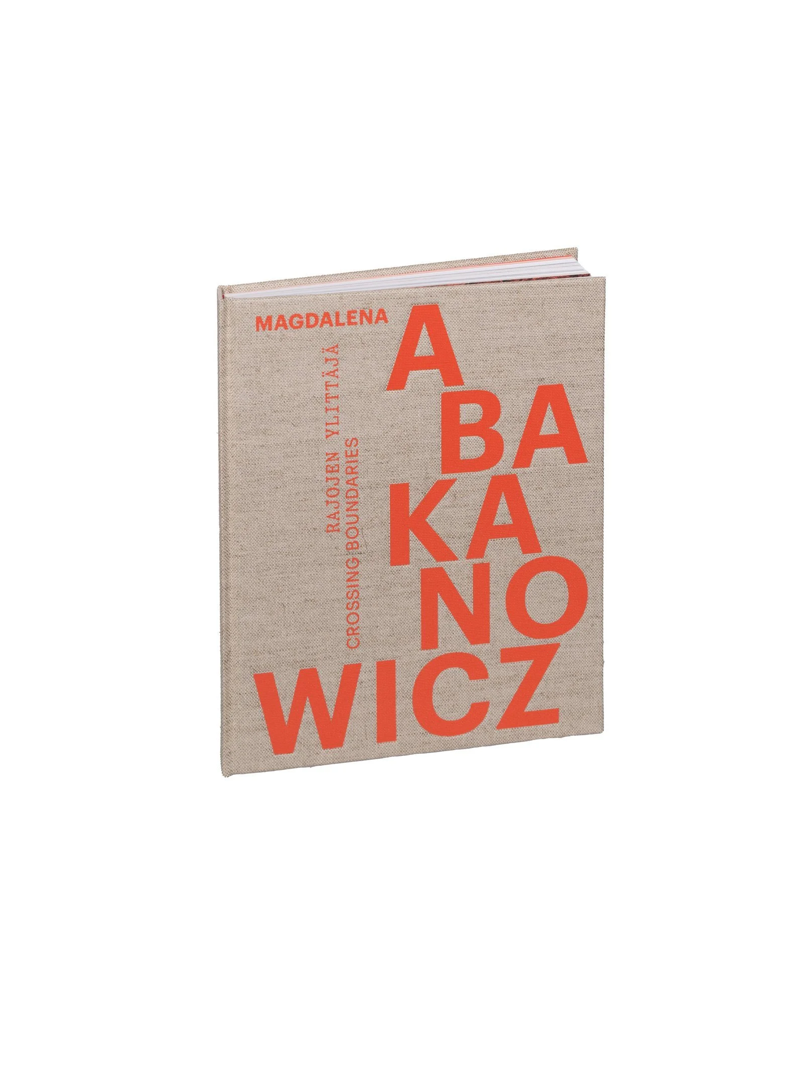 Close-up of a beige fabric-covered book with red text on the front cover, with the title "Crossing Borders" and the author's name, Magdalena Abakanowicz, in uppercase letters. An exhibition book in Helsinki art museum