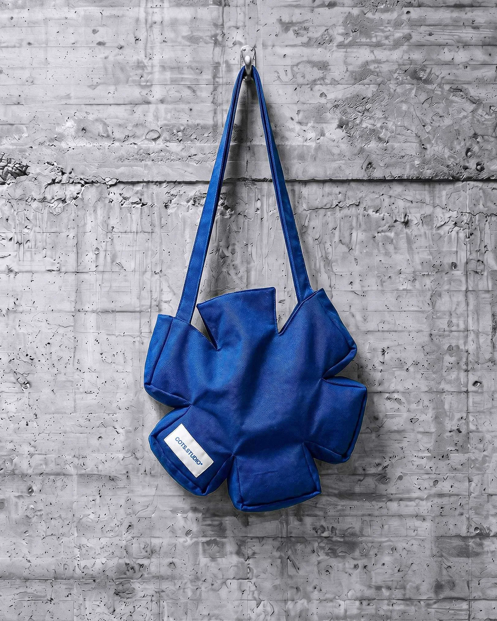 ASTERISK BAG COTS.STUDIO blu appesa, vista completa con forma ad asterisco e manici lunghi