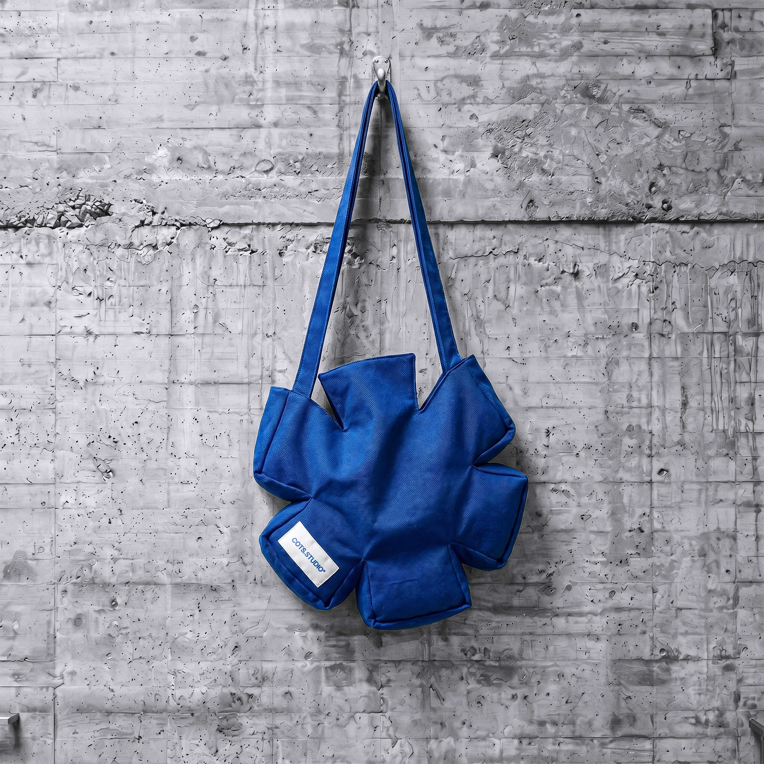 ASTERISK BAG COTS.STUDIO blu appesa, vista completa con forma ad asterisco e manici lunghi
