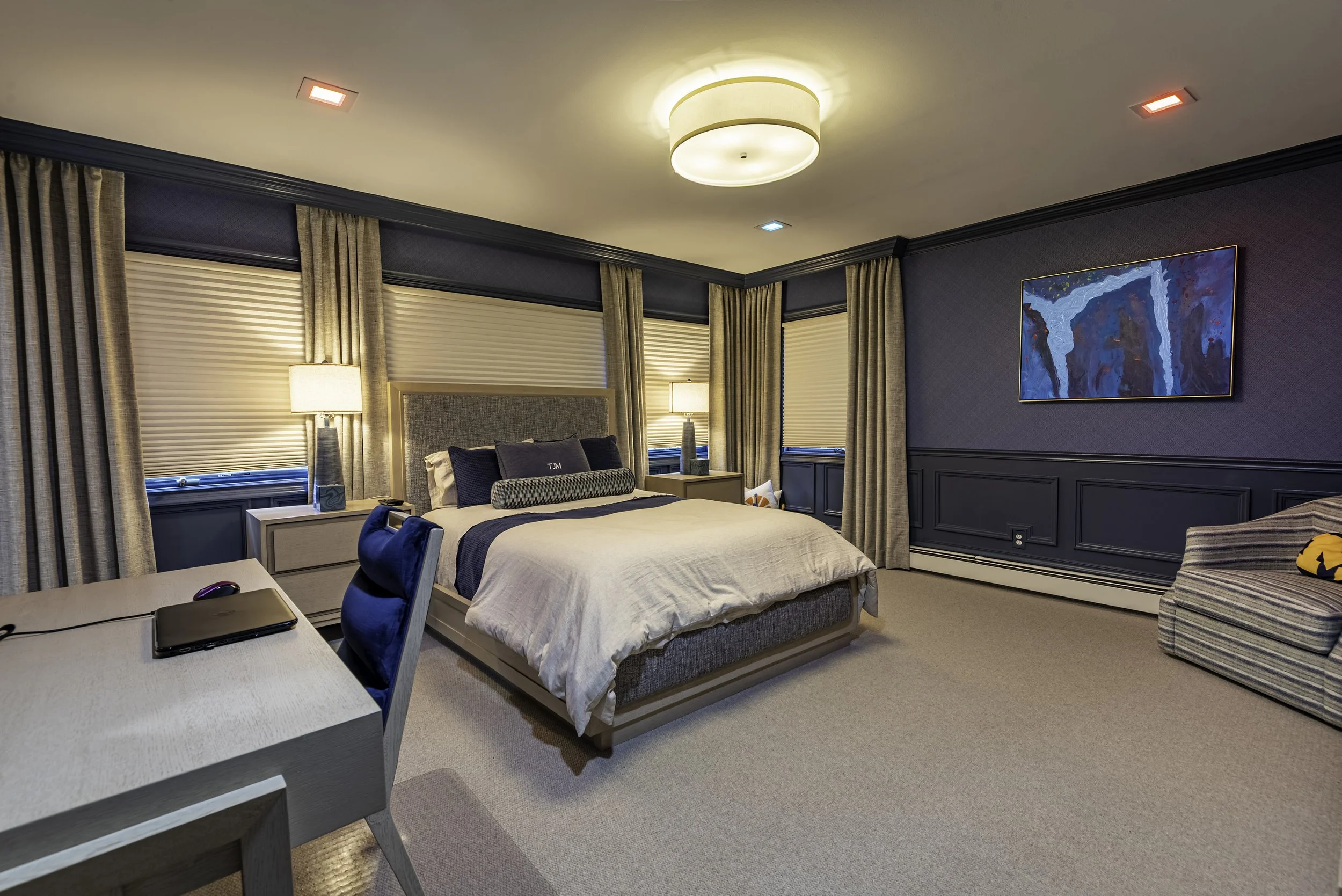 Luxury modern bedroom interior with elegant lighting, blue accent walls, custom drapery, and designer furniture captured for professional real estate photography in New York.