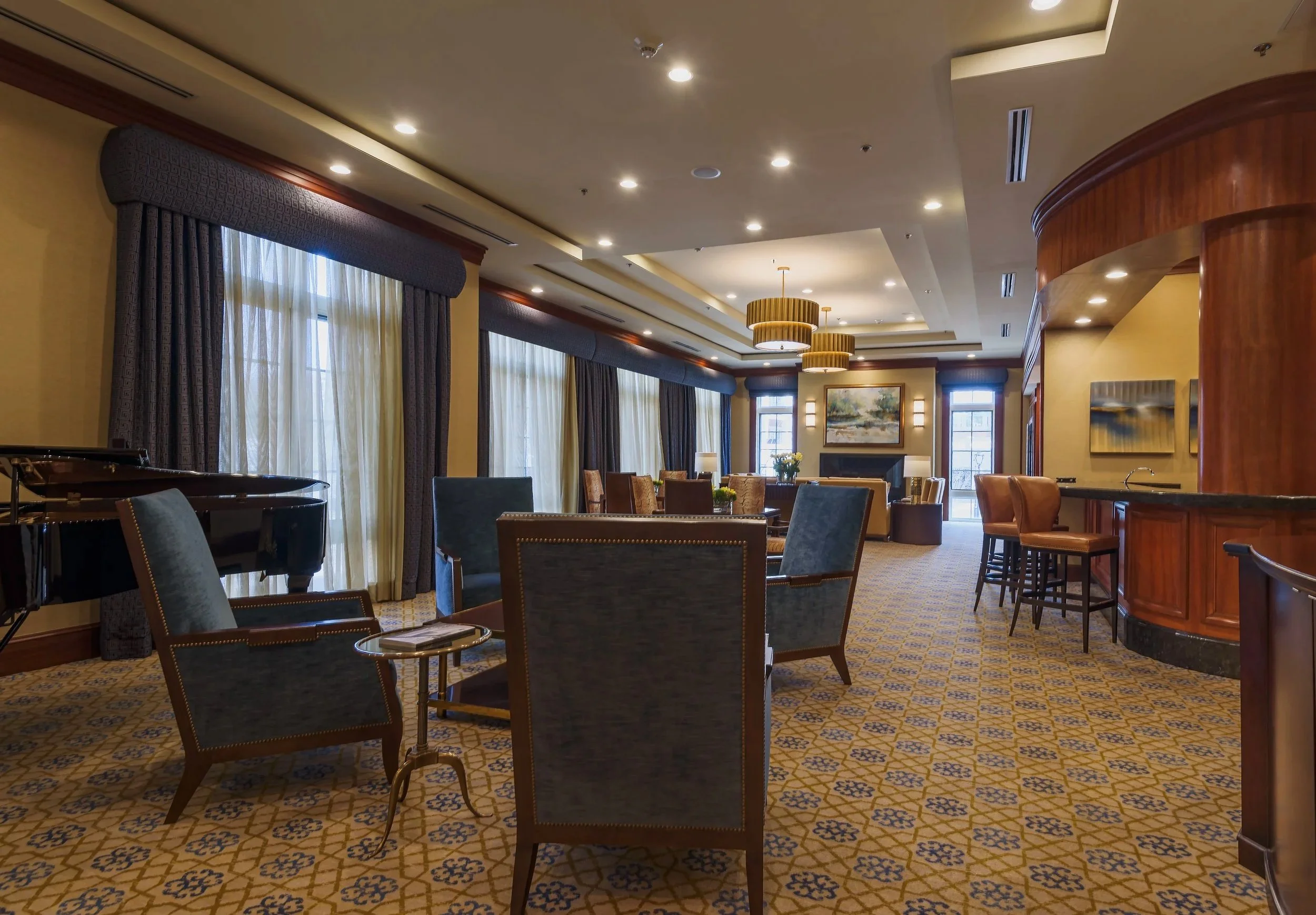 Luxury condominium lounge interior at the Ritz in Long Island featuring seating area, piano, bar, and architectural lighting design.