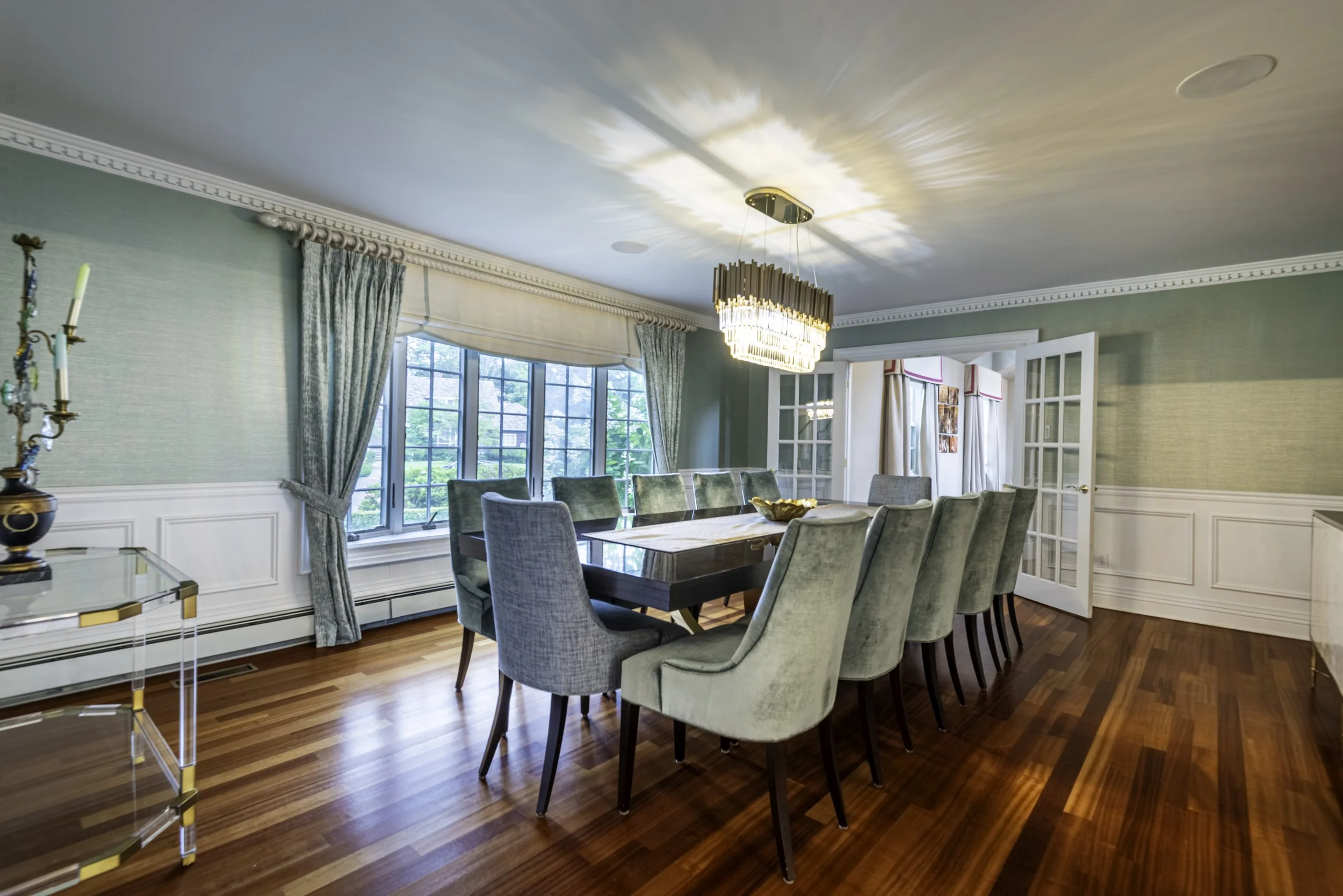 Professional real estate dining room photography featuring modern decor, elegant chandelier, hardwood floors, and open concept home interior in New York.