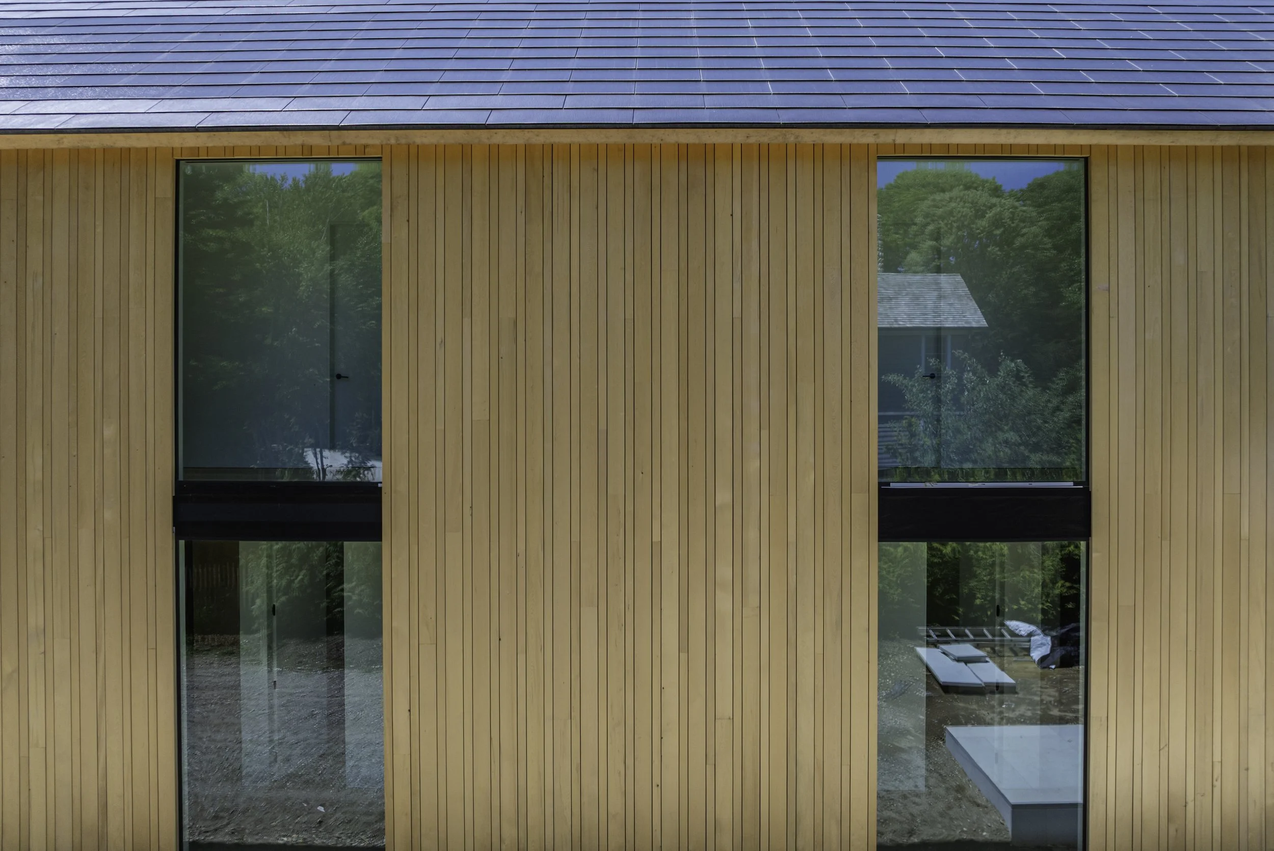 Modern wood-clad exterior façade with large vertical windows documented during residential construction.