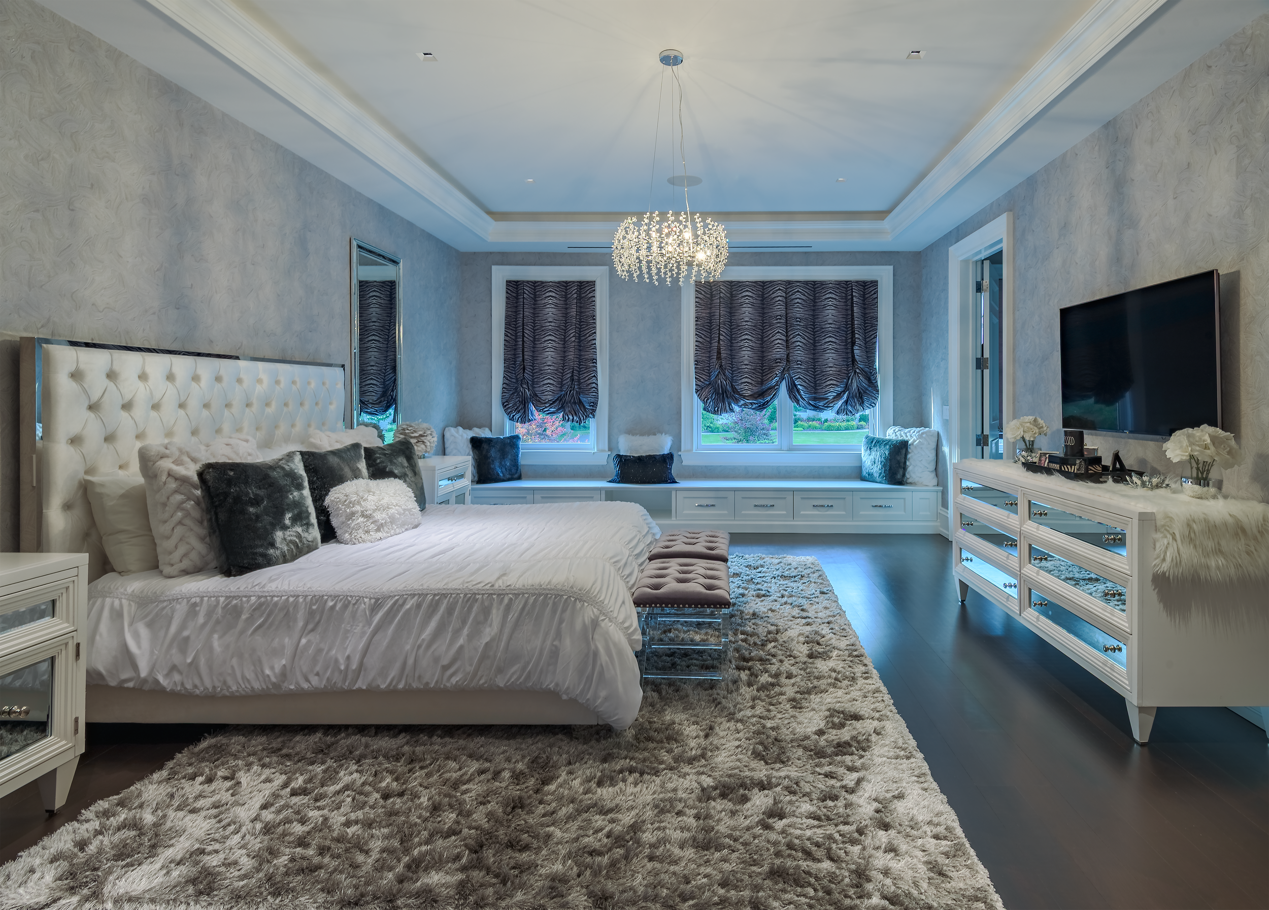 Luxury foyer with black and white checker floor, curved staircase, designer lighting, and elegant interior architecture.