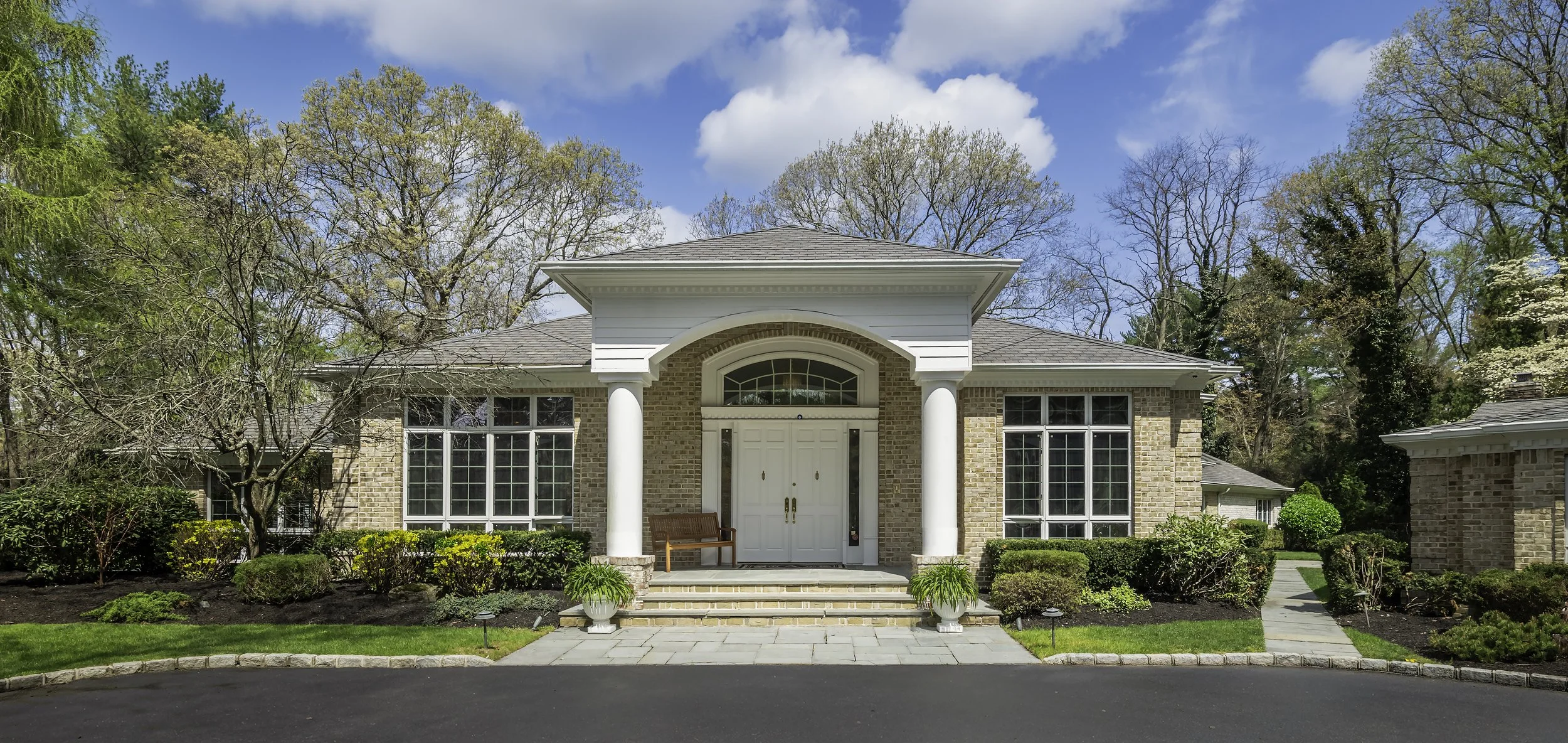 Architectural photography of a luxury brick estate entry portico with white columns and arched transom window, Long Island, NY — Palma Design