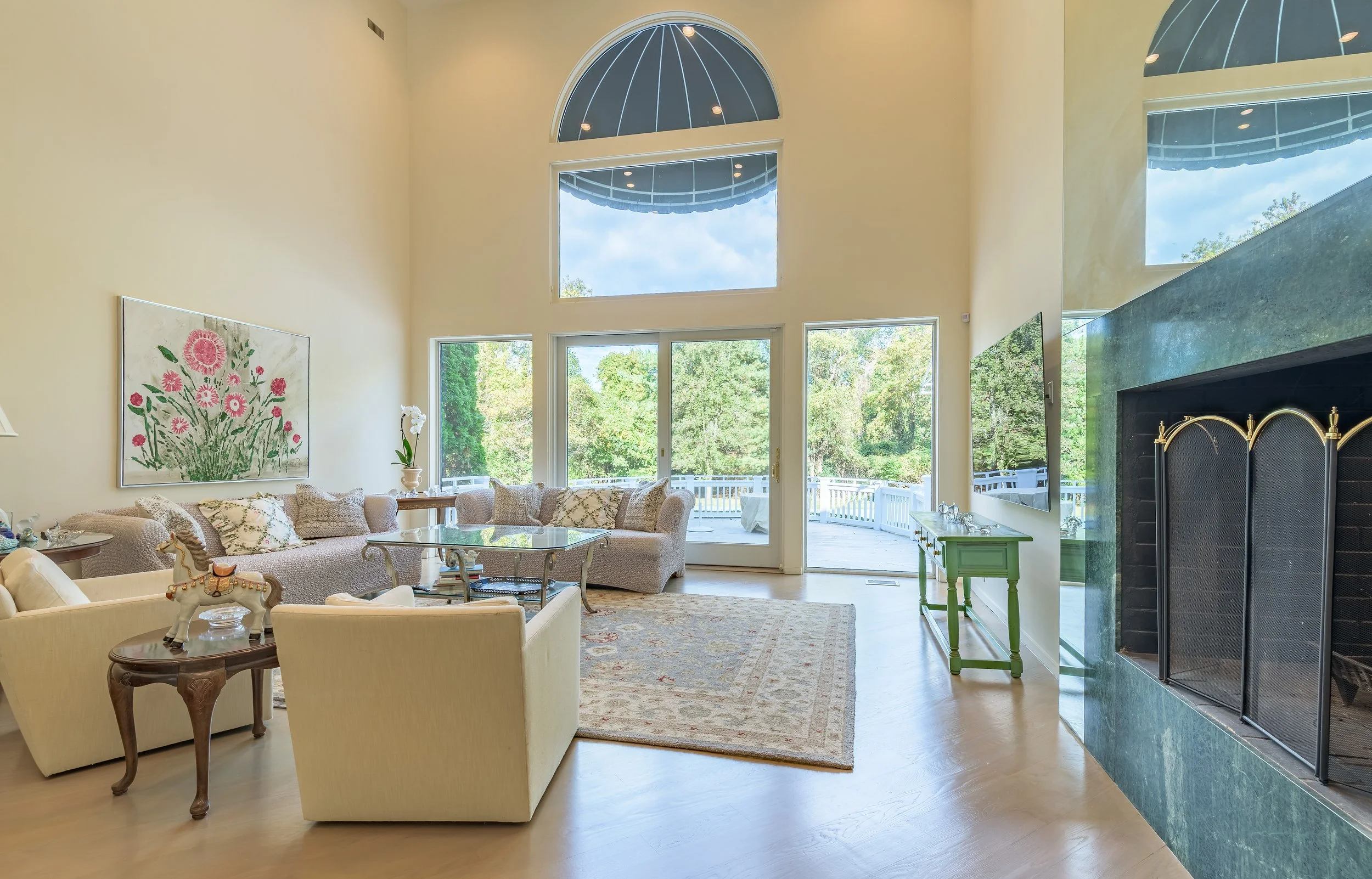 Luxury living room interior with high ceilings, large windows, elegant décor, natural light, and outdoor deck view — photographed for real estate and architectural marketing.