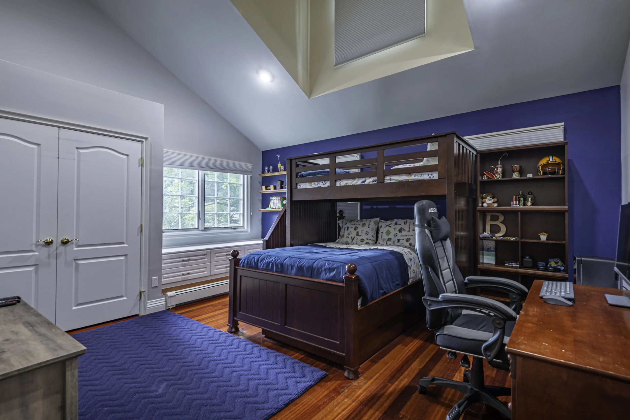 Modern blue bedroom interior with wood furniture, home office desk, hardwood floors, and accent lighting, photographed for professional real estate in New York.