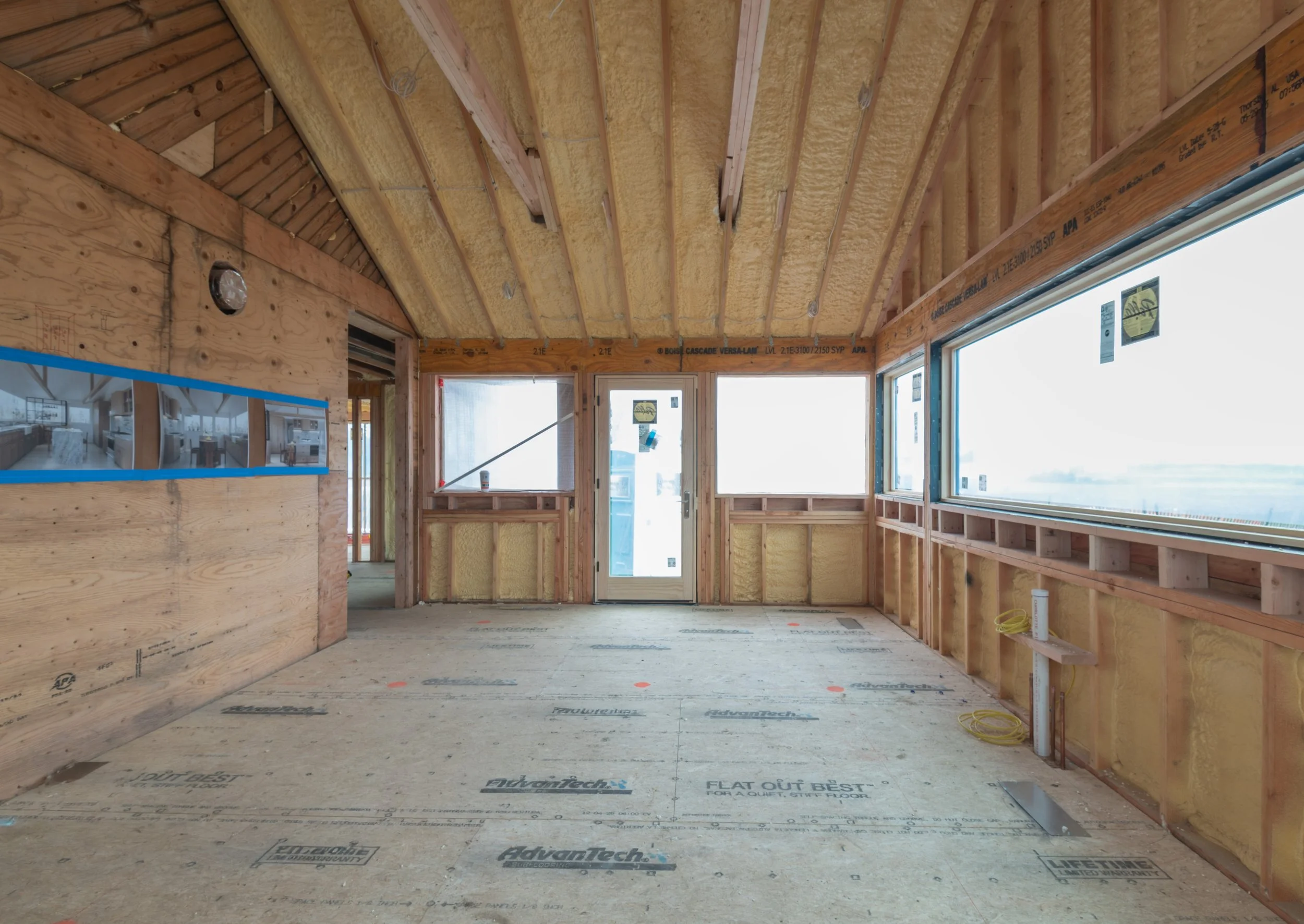 Kitchen framing in a Hamptons gut renovation with spray foam insulated rafters, a new picture window and rough plumbing before cabinets and stone were installed