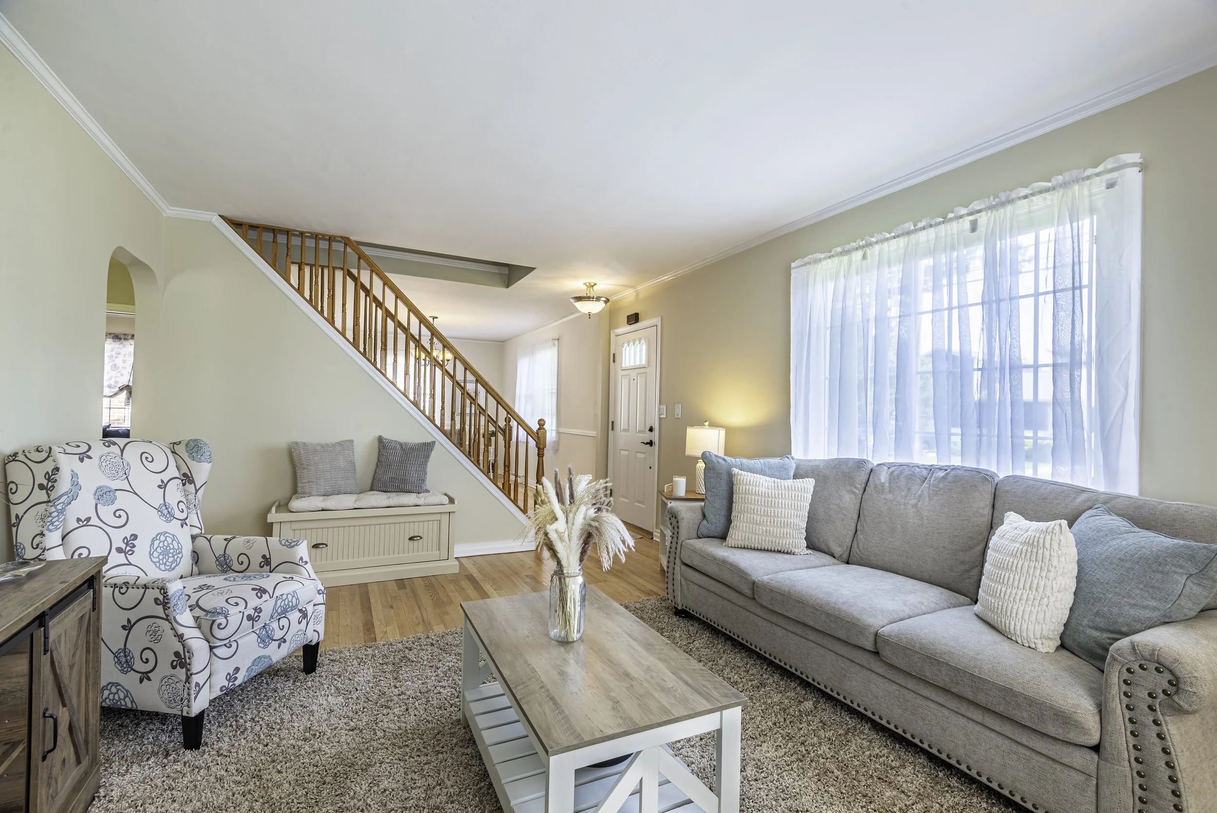 Charming living room with staircase, built-in seating nook, gray sofa, and stylish farmhouse-style decor.