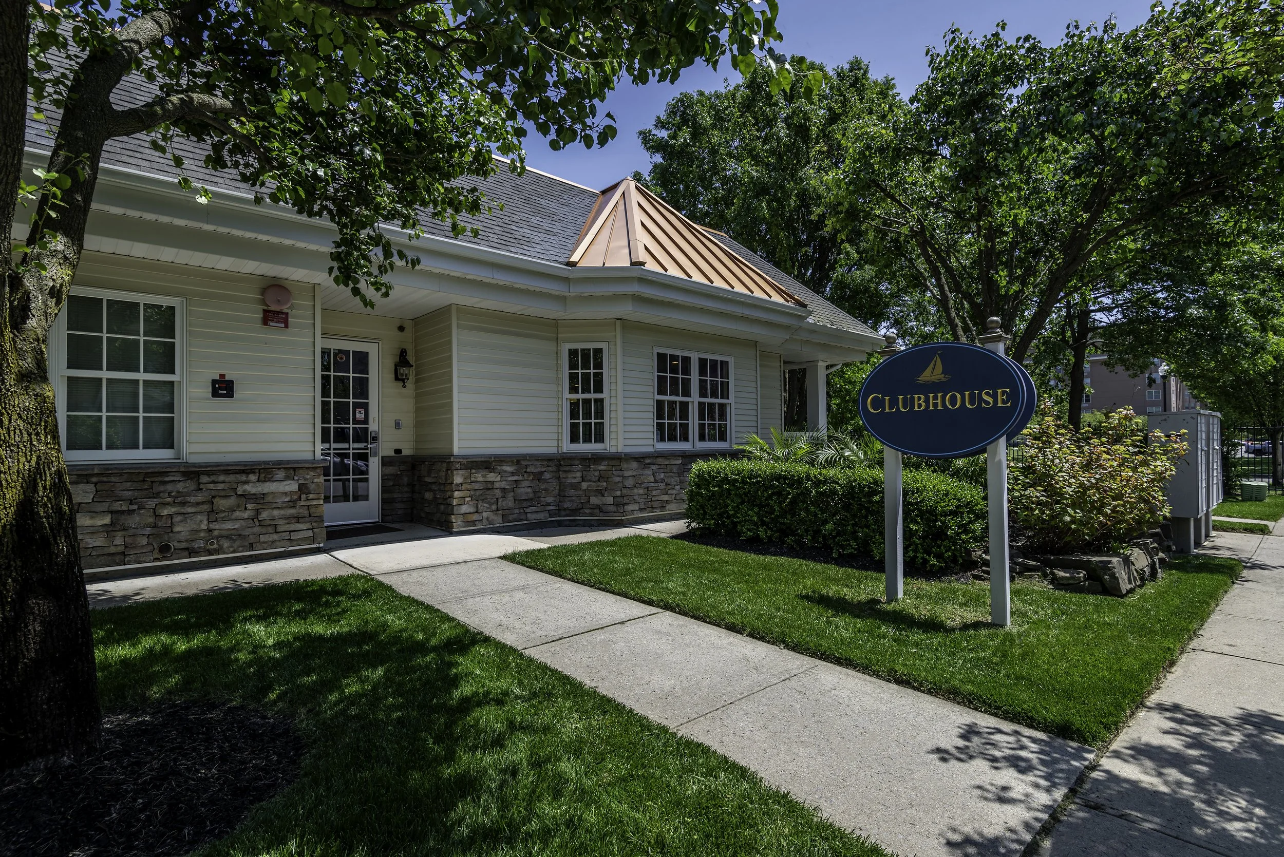 Exterior of The Addison clubhouse in a luxury senior living community with landscaped lawn and trees.