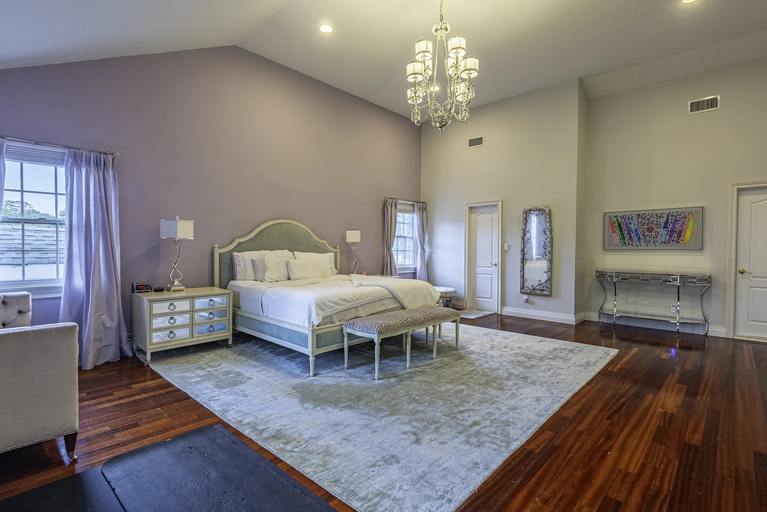 Elegant bedroom interior with stylish decor, custom headboard, warm lighting, and upscale design elements captured by professional real estate photographer in New York.